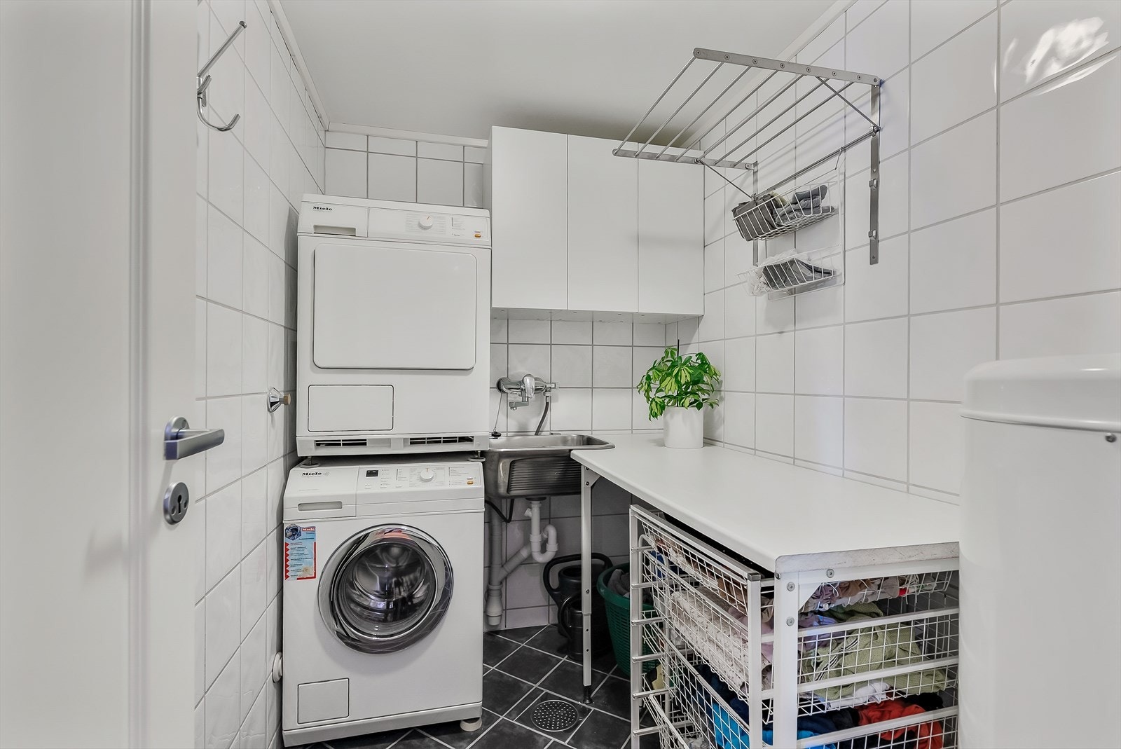 Separat vaskerom med flislagt gulv med gulvvarme, skyllekar og opplegg for vaskemaskin og tørketrommel. Galleribilde