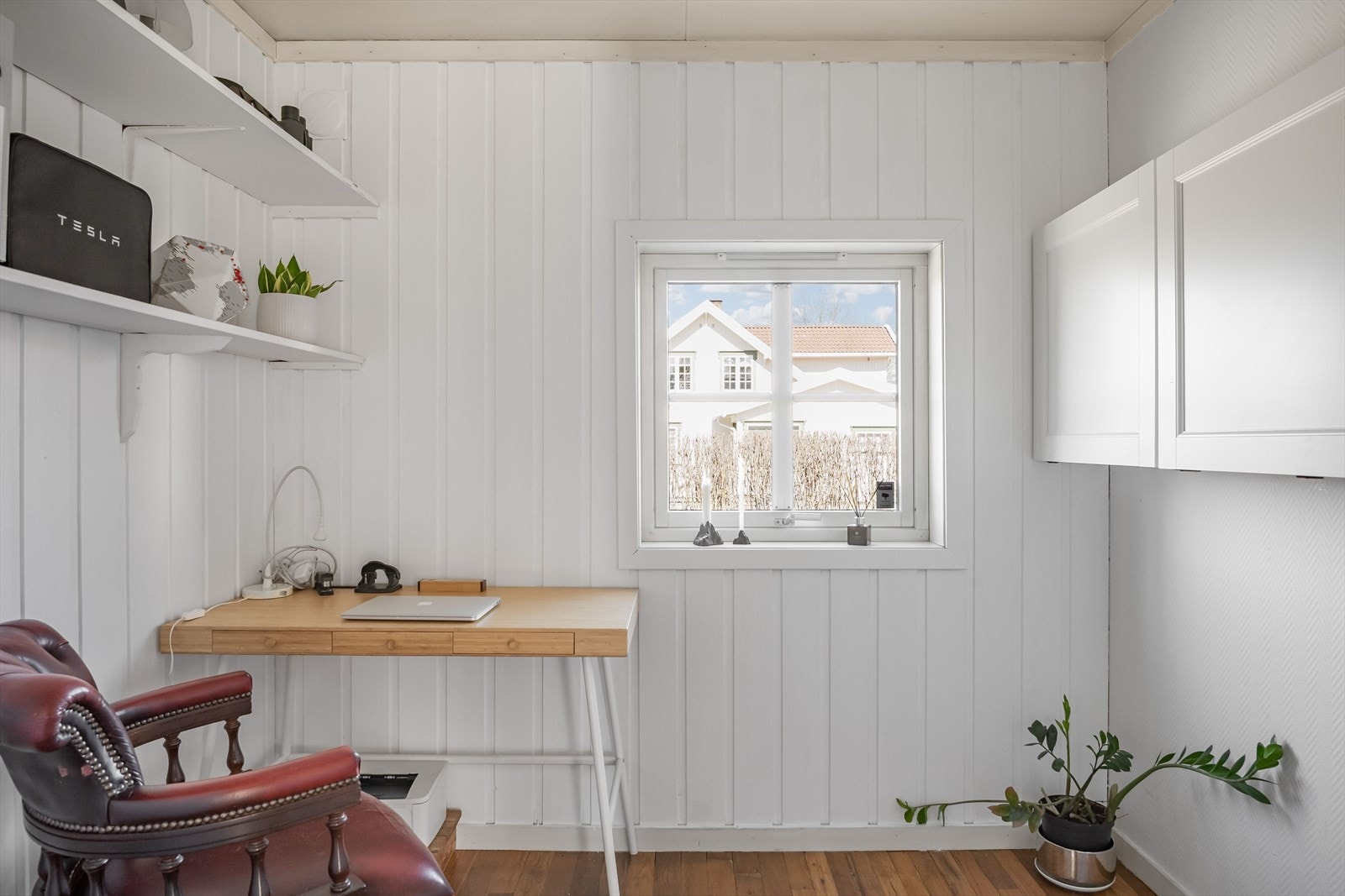 Kontoret har malt panel på veggene og gulv av heltregulv. Galleribilde