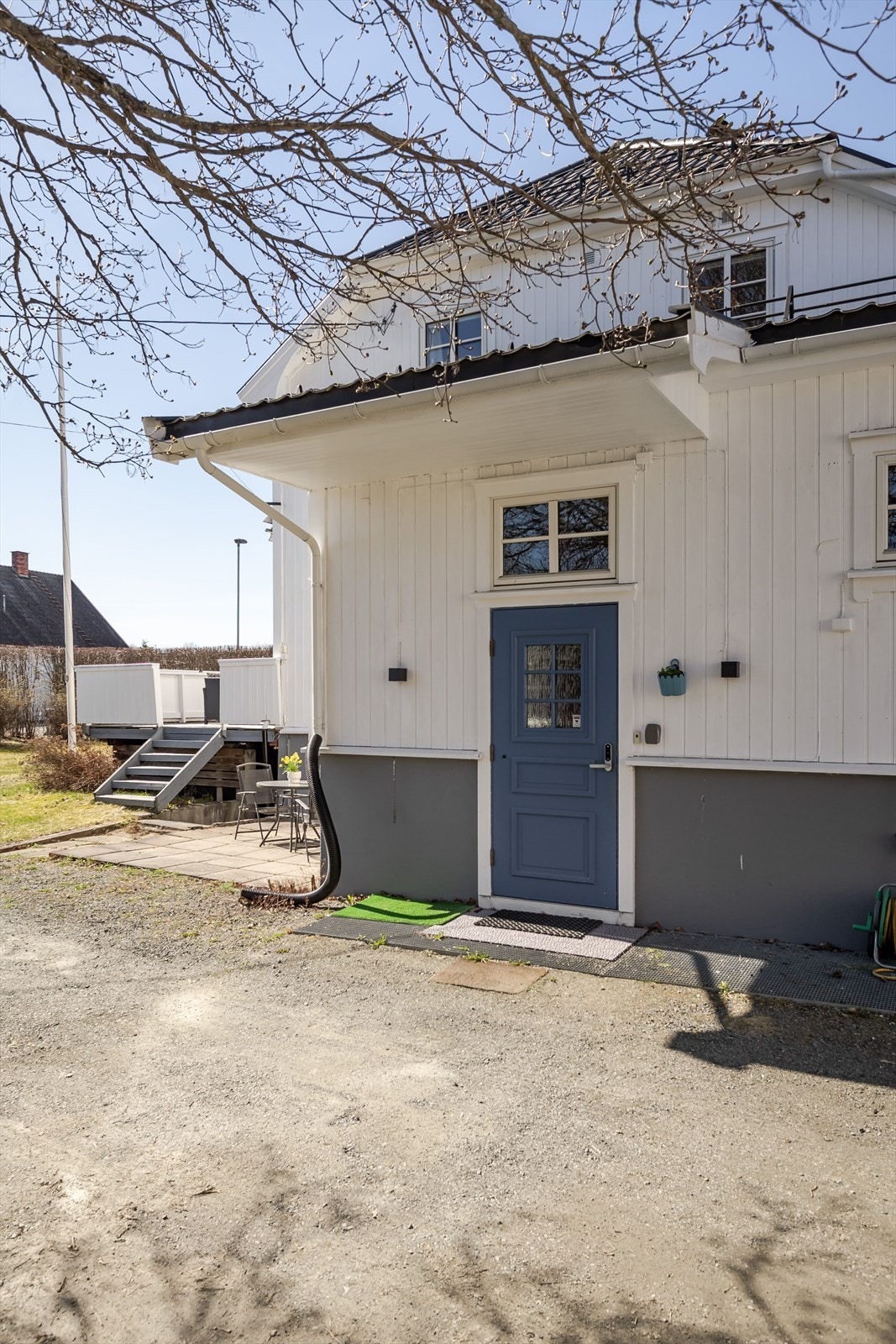 Takoverbygg ved inngangsdøren og en fin, hellelagt uteplass i kroken rundt hjørnet. Galleribilde
