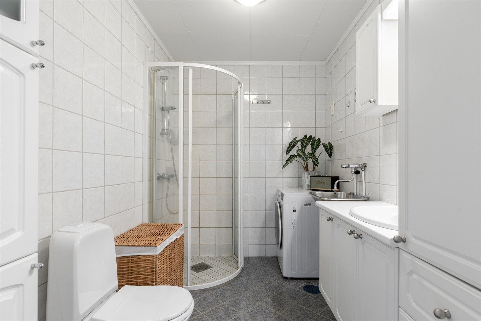 Flislagt bad med dusjhjørne og lys baderomsinnredning i tidløst design Galleribilde