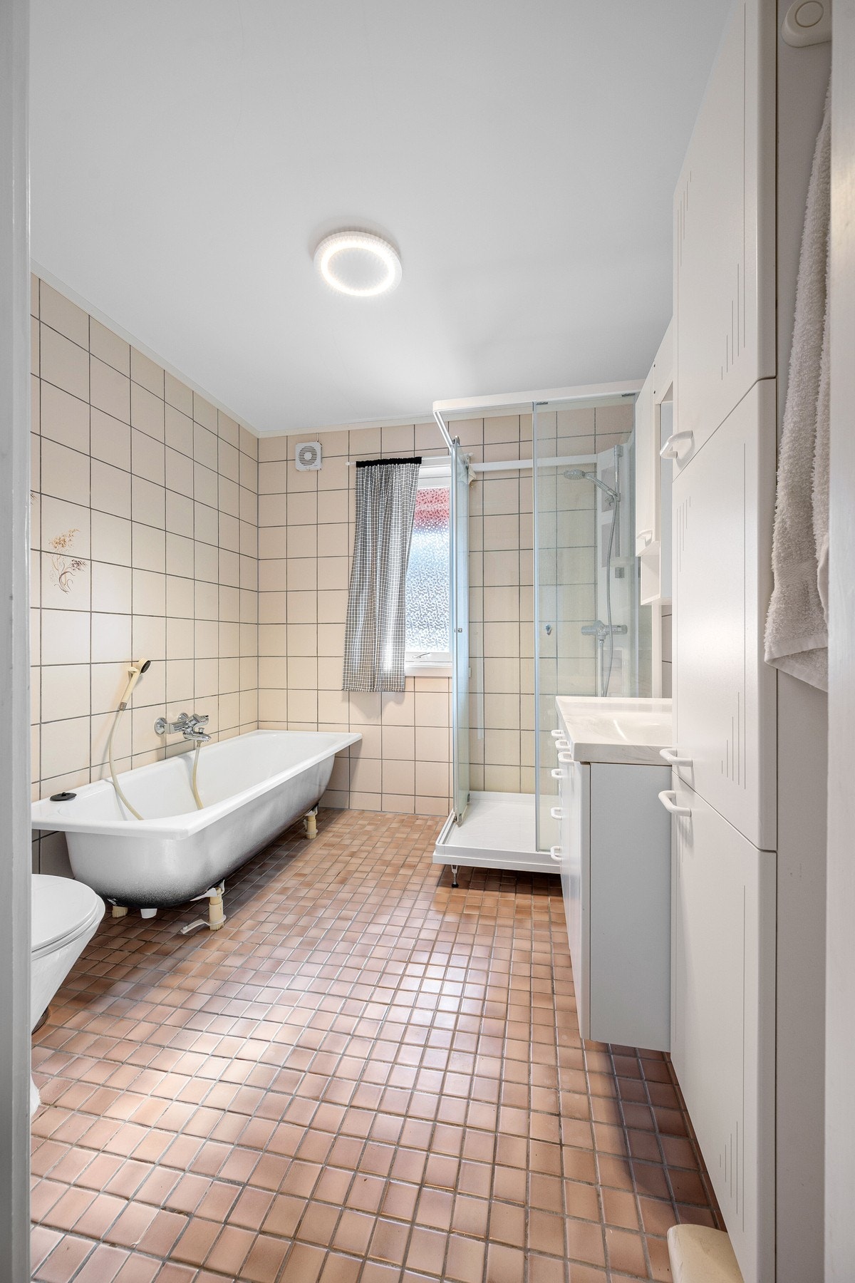 Flislagt bad av god størrelse med plass til både dusjkabinett og badekar Galleribilde
