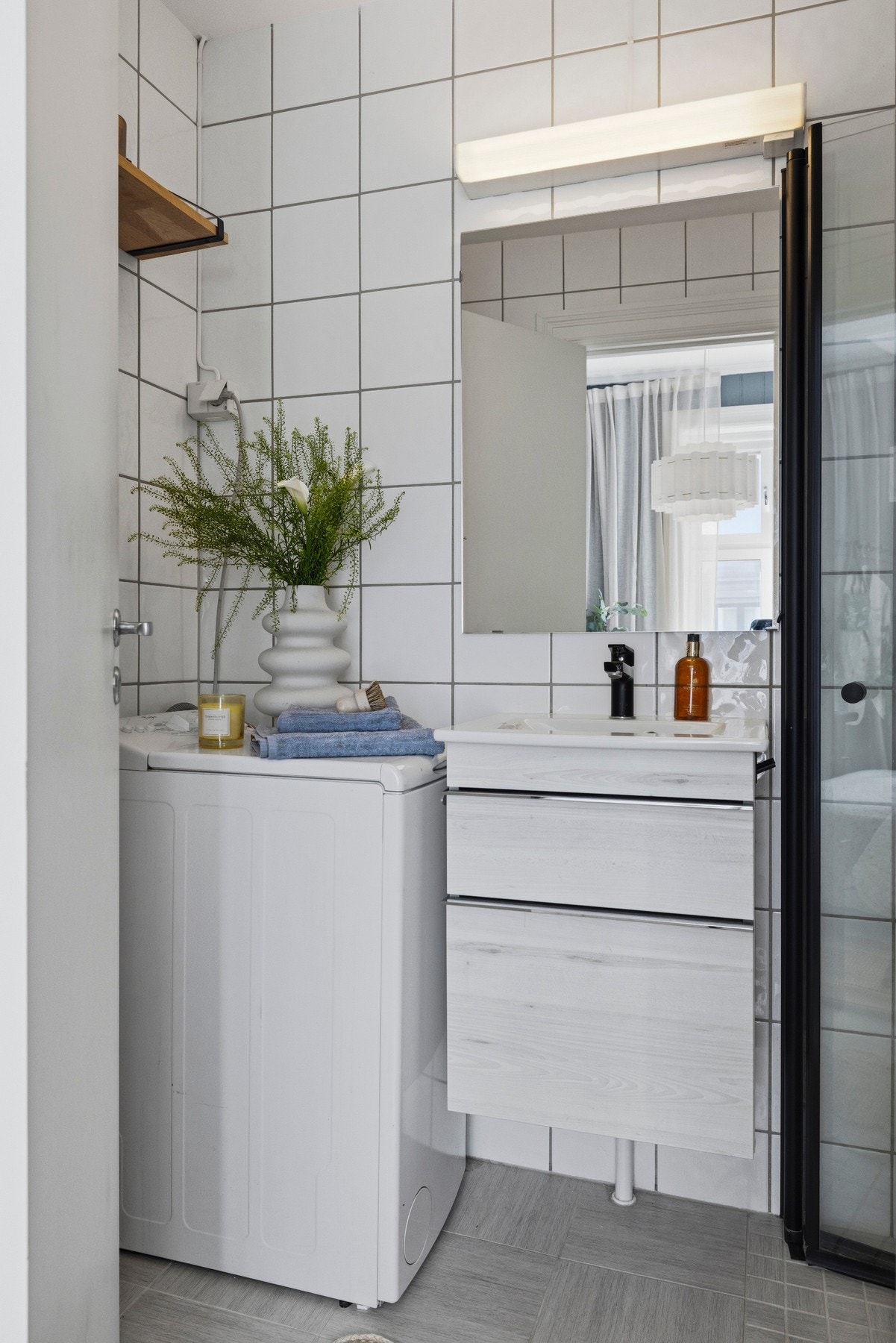 Videre er badet utstyrt med servant, dusj på gulv og opplegg for vaskemaskin Galleribilde