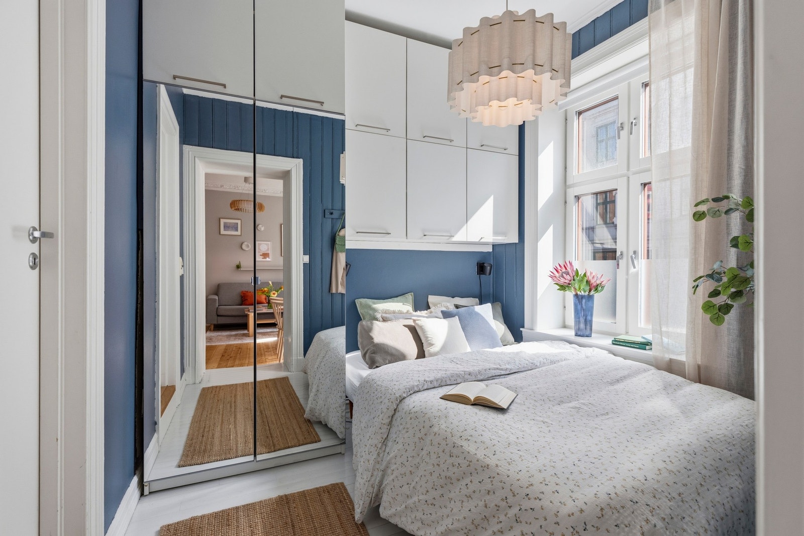Det er en garderobe med speilfronter og ekstra skap over sengen Galleribilde