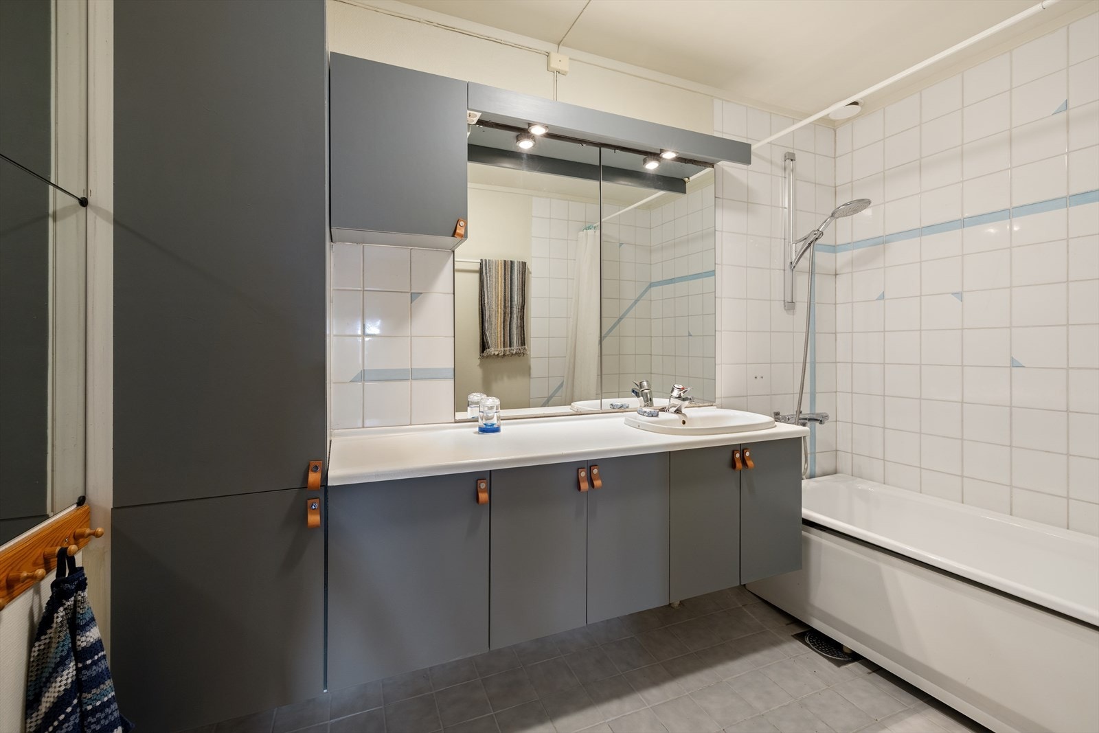 Badet i underetasjen har fliser på gulv med gulvvarme. Veggene er kledd med fliser og malt tapet. Galleribilde