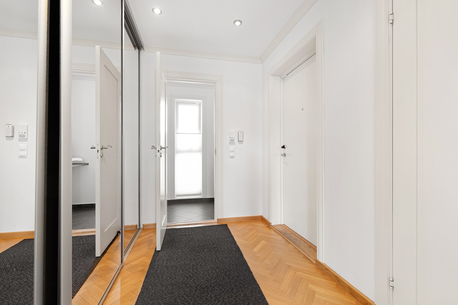 Innvendig trapp leder rett fra garasjeanlegget og opp til leiligheten. Hallen har speil skyvedørsgarderobe Galleribilde