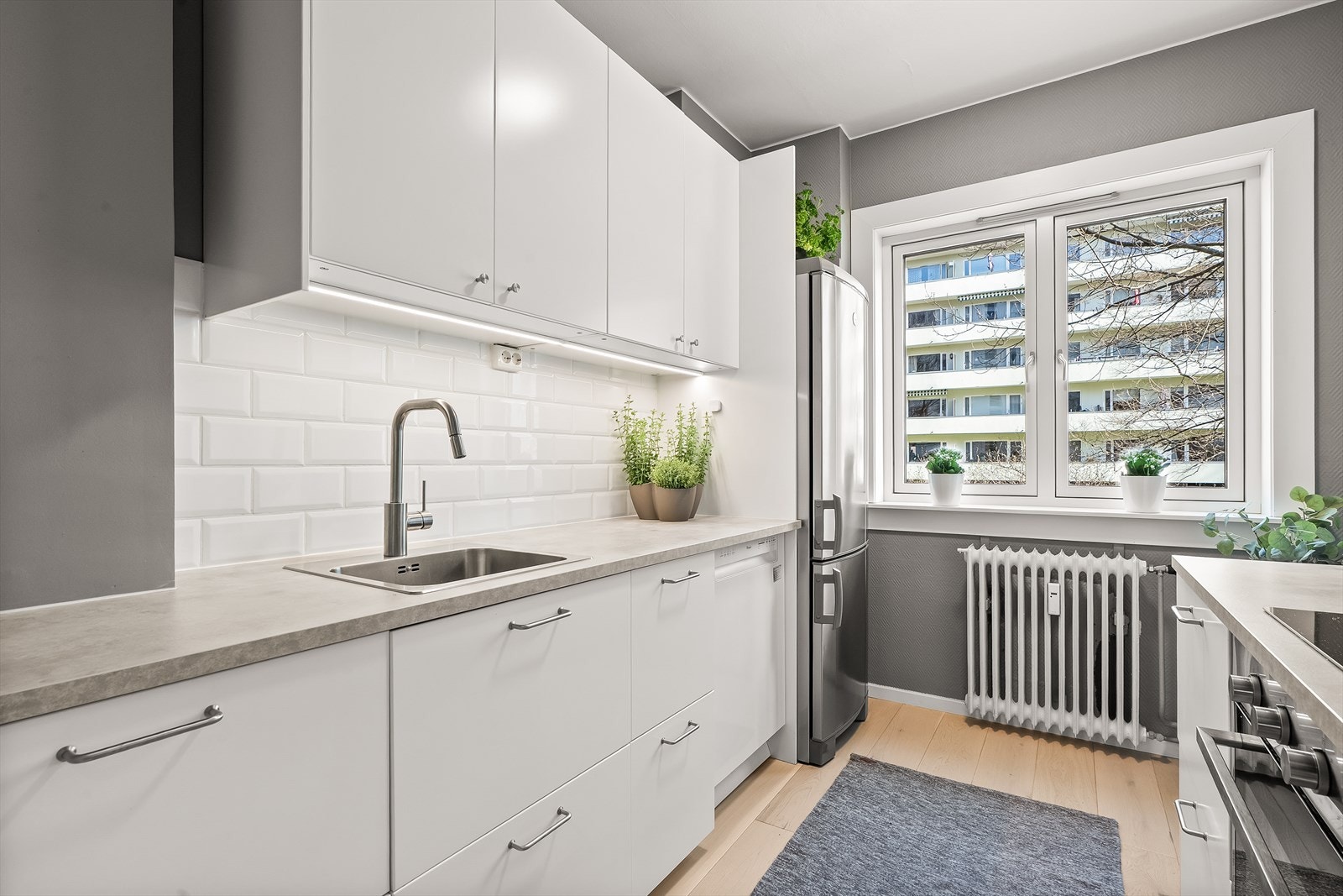 Innredningen har glatte fronter og laminat benkeplate med nedfelt vaskekum. Stort vindu på kjøkkenet sørger også for rikelig med lys og gode luftemuligheter. Galleribilde