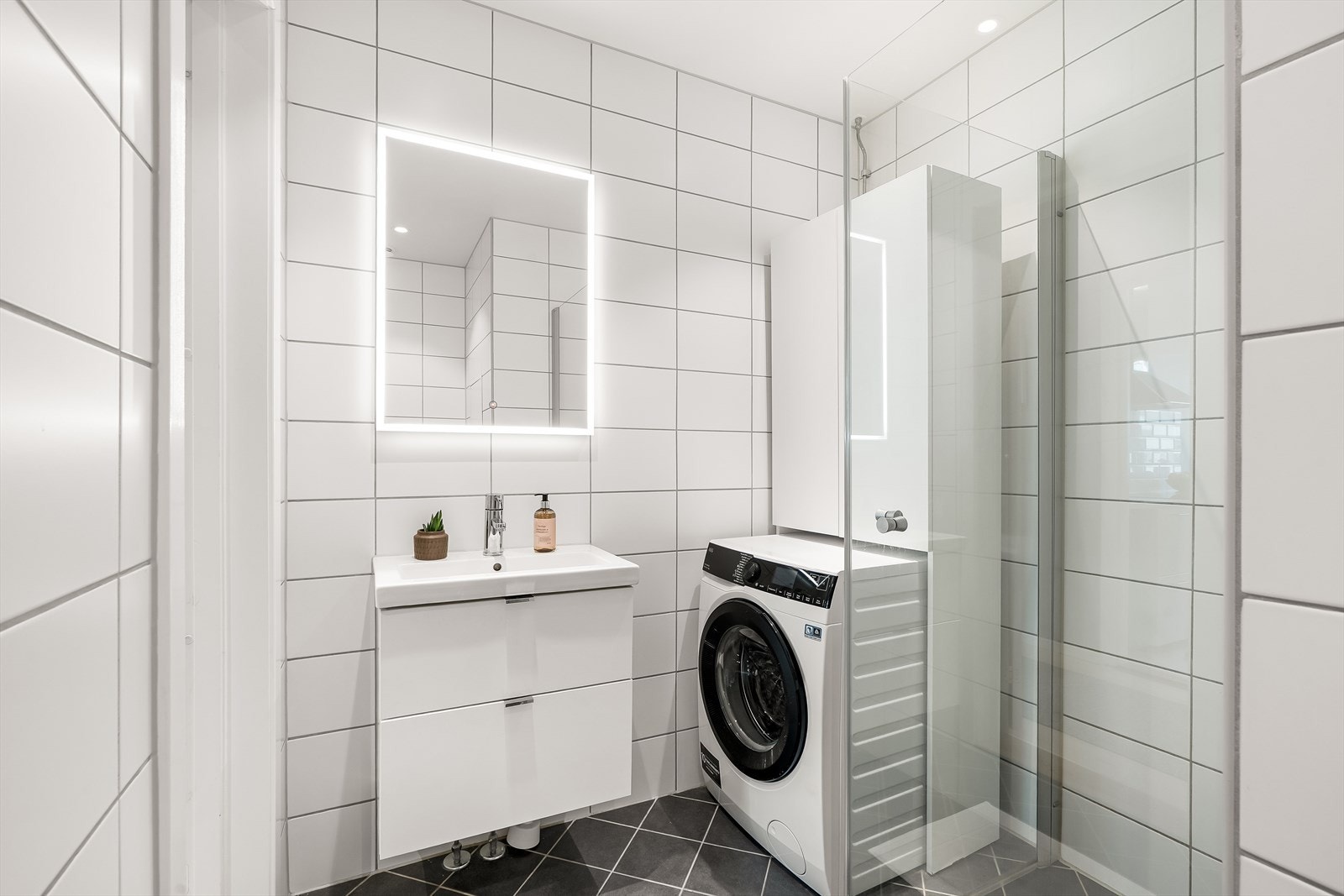 Et lyst og pent flislagt baderom, pusset opp i regi av sameiet i 2019 med opplegg for vaskemaskin. Galleribilde