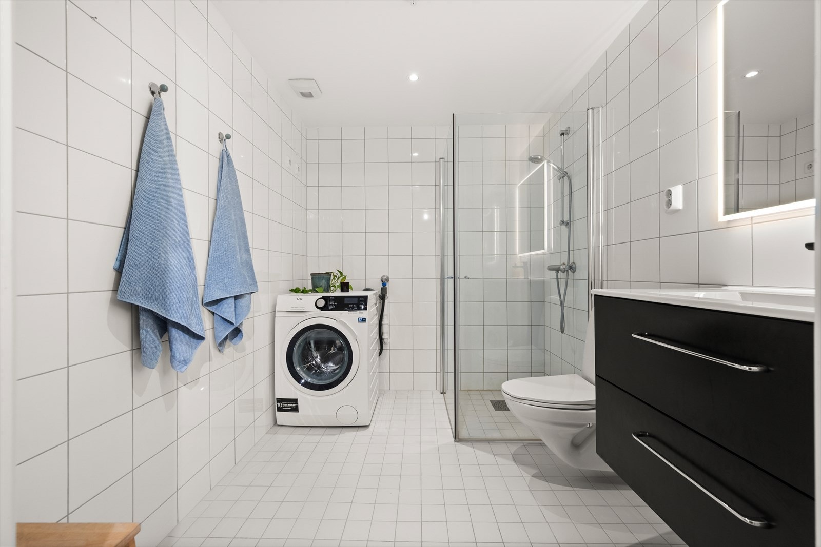 - Badet er innredet med benkeskap med servant, dusjdører, vegghengt toalett og opplegg for vaskemaskin - Galleribilde