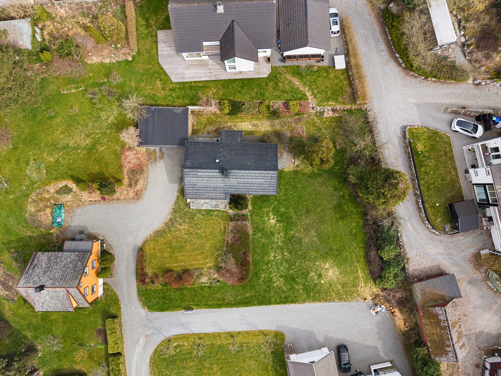Tomt på 1228 m² med oppgruset gardsrom og hage over flere nivåer. Innslag av trær, busker og bed. Galleribilde