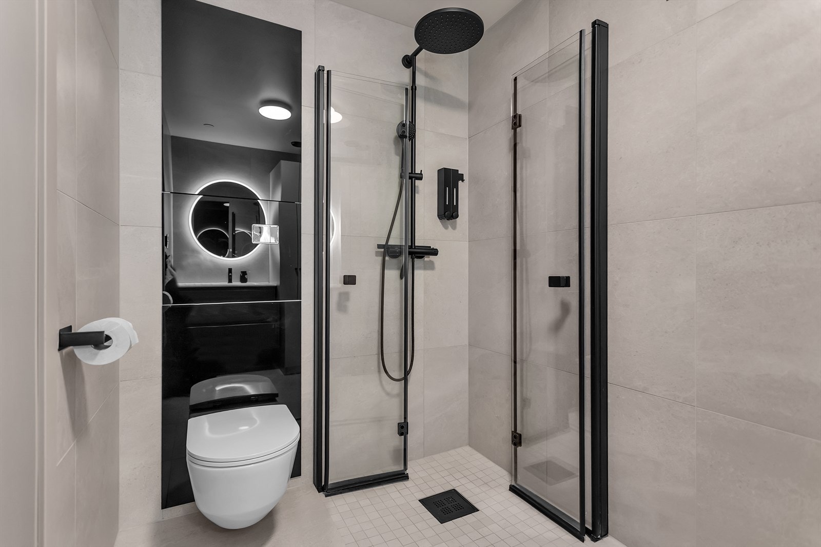Badet er innredet med et delikat design, hvor store 60x60 fliser på gulv og vegger kombineres med mosaikkfliser i dusjsonen for en moderne og eksklusiv finish. Dusjnisjen er utstyrt med plassbesparende glassvegger og en stilfull "fossefall"-dusj. Galleribilde