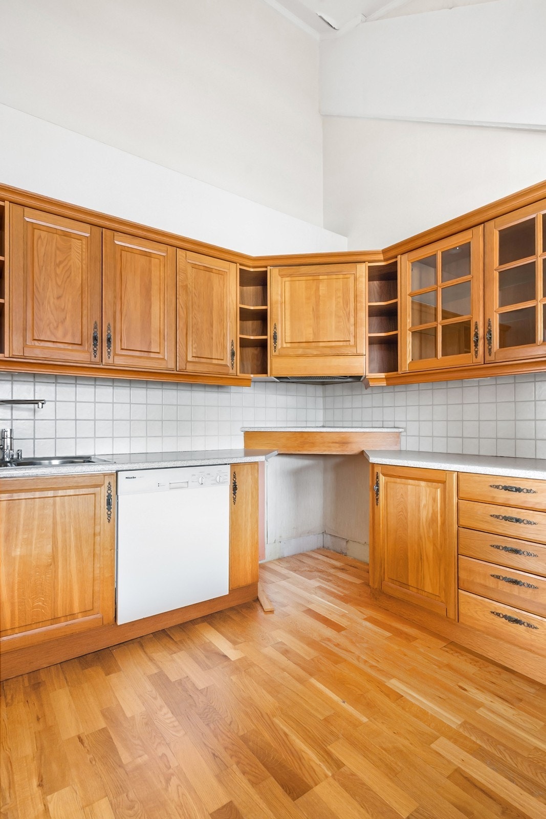 Innredningen har fronter i heltre kombinert med laminat benkeplate, og fliser på vegg over benk. Galleribilde
