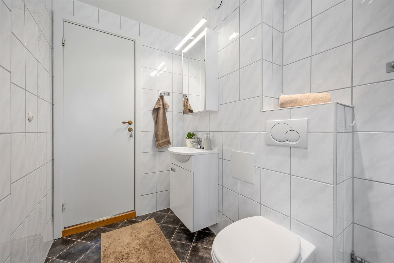 Badet er utstyrt med vegghengt toalett og servant med underskap. Galleribilde