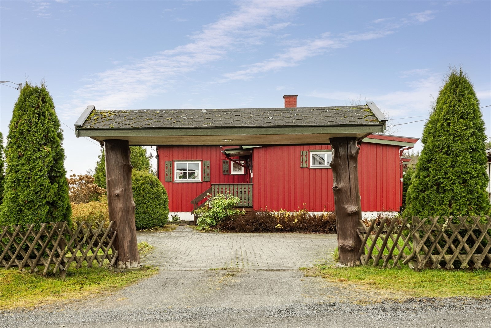 Eiendommen har en steinbelagt gårdsplass og fin innrammingen av tomten med gjerde og busker. Galleribilde