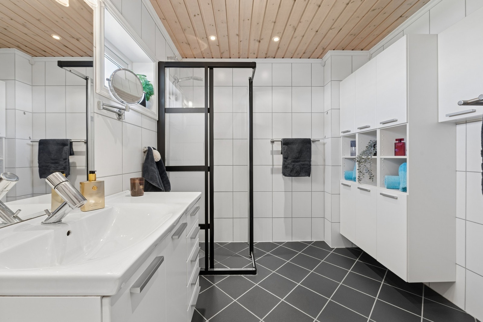 Badet har en praktisk og romslig utforming med flislagte overflater og gulvvarme for god komfort. Galleribilde