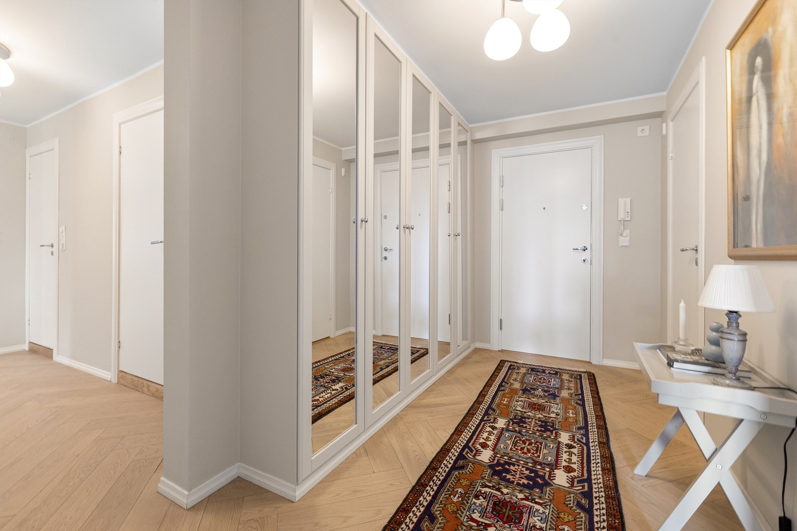 En romslig entré med en stor garderobeløsning med speilfronter. Gulvvarme gir en lun velkomst. Galleribilde