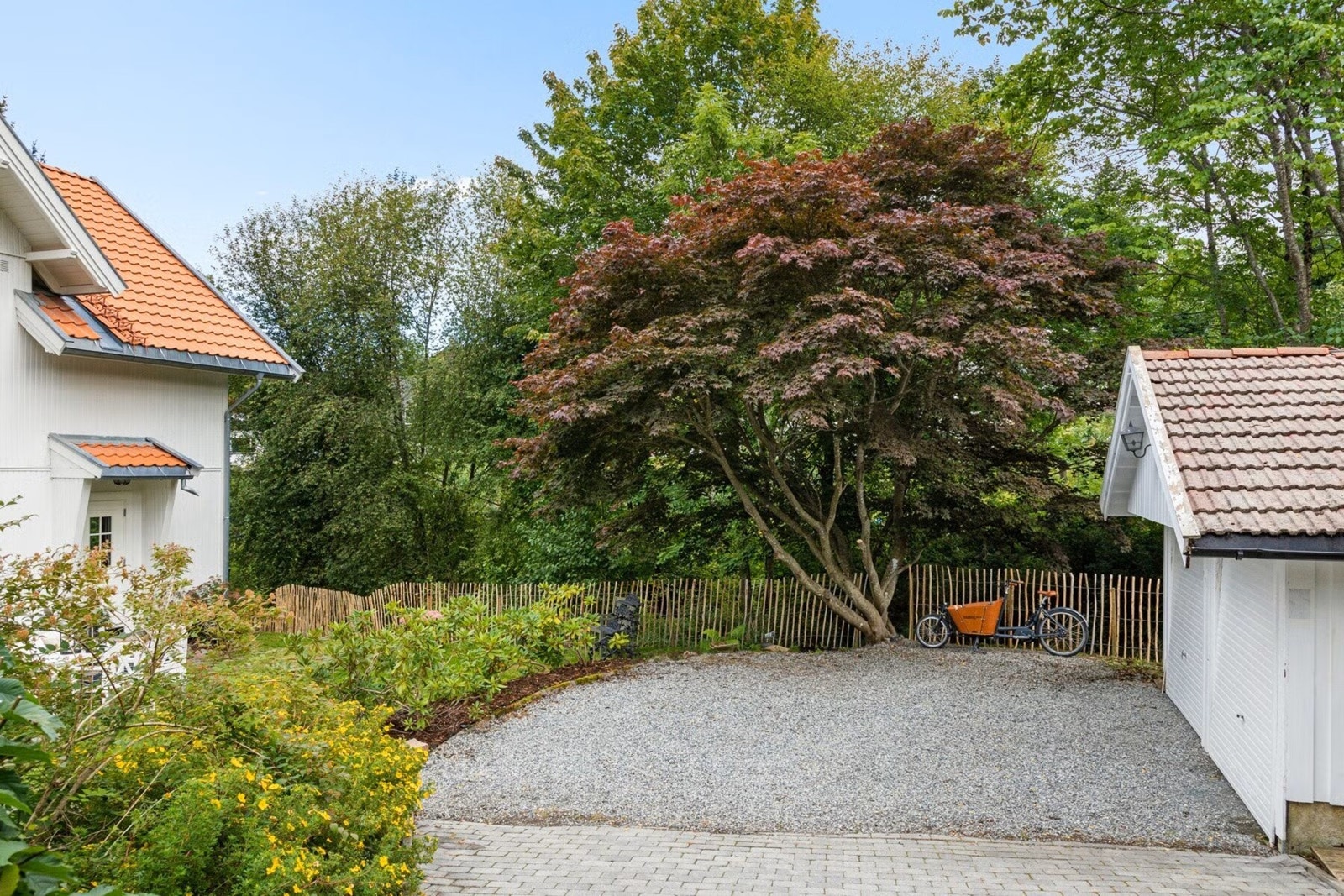 Gårdsplass med parkering i dobbelgarasje. Lader for el-bil ble montert i 2023. Galleribilde
