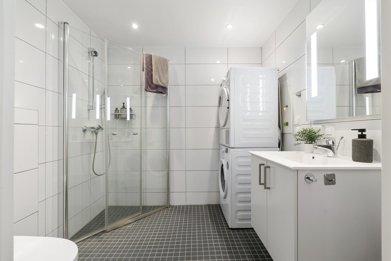 Det 4 m² store badet fremstår som innbydende med helflisede overflater, behagelig gulvvarme og downlights i tak. Galleribilde