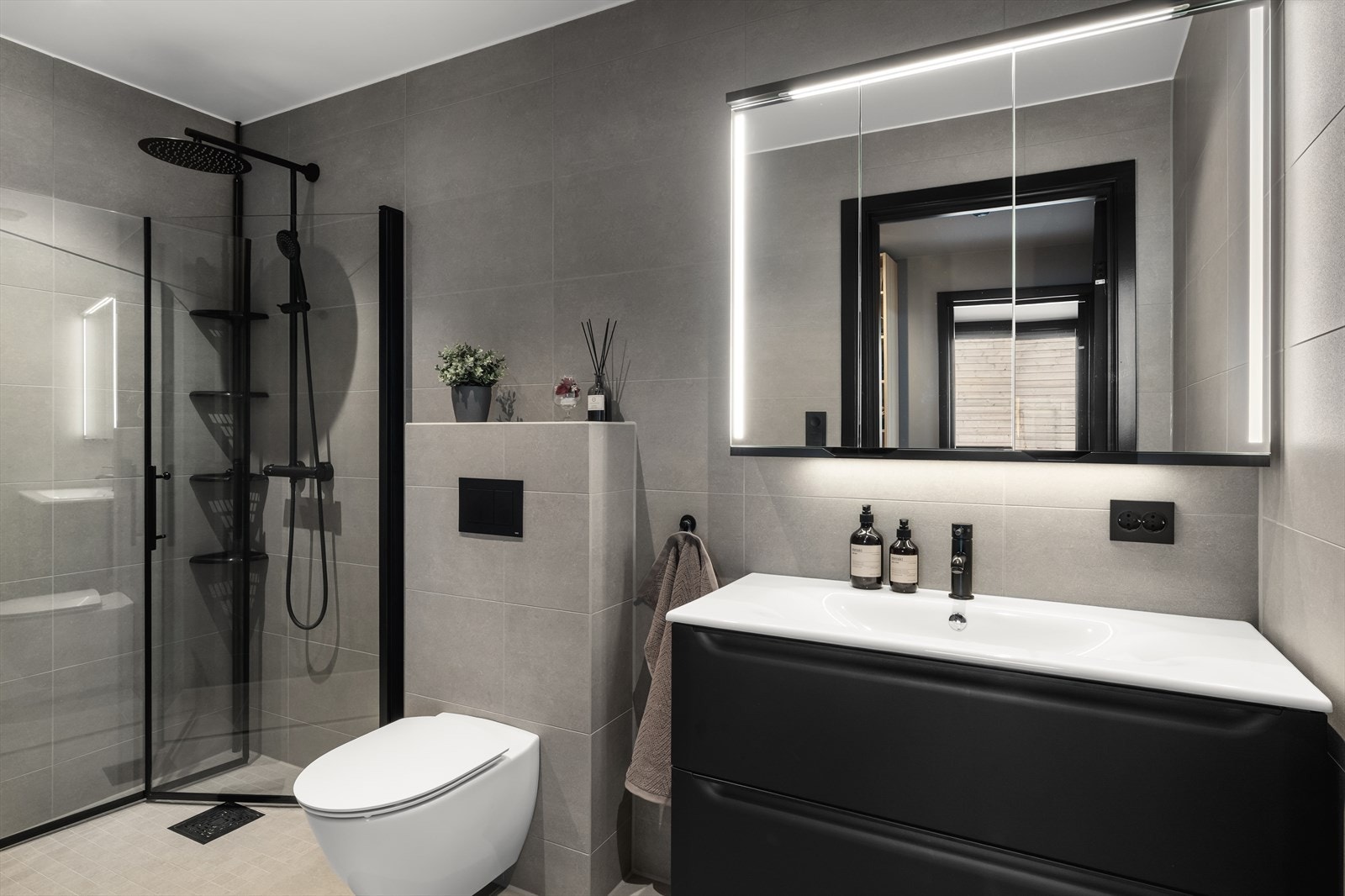 Det flotte, helflisede badet har moderne detaljer som vegghengt toalett, dusjhjørne og stilfull baderomsinnredning i svart utførelse. Galleribilde