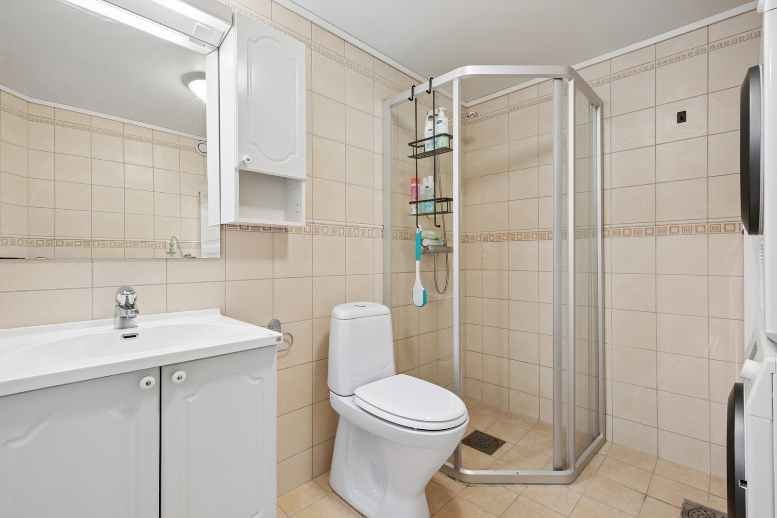 Badet er innredet med dusjhjørne, gulvstående toalett og baderomsinnredning med heldekkende servant. Galleribilde