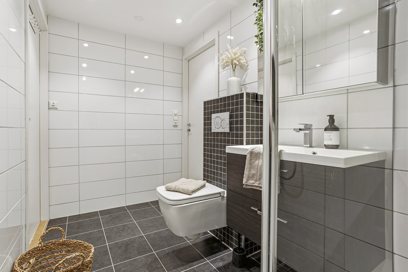 Badet er utstyrt med vegghengt toalett, servant med innredning og dusj. Galleribilde