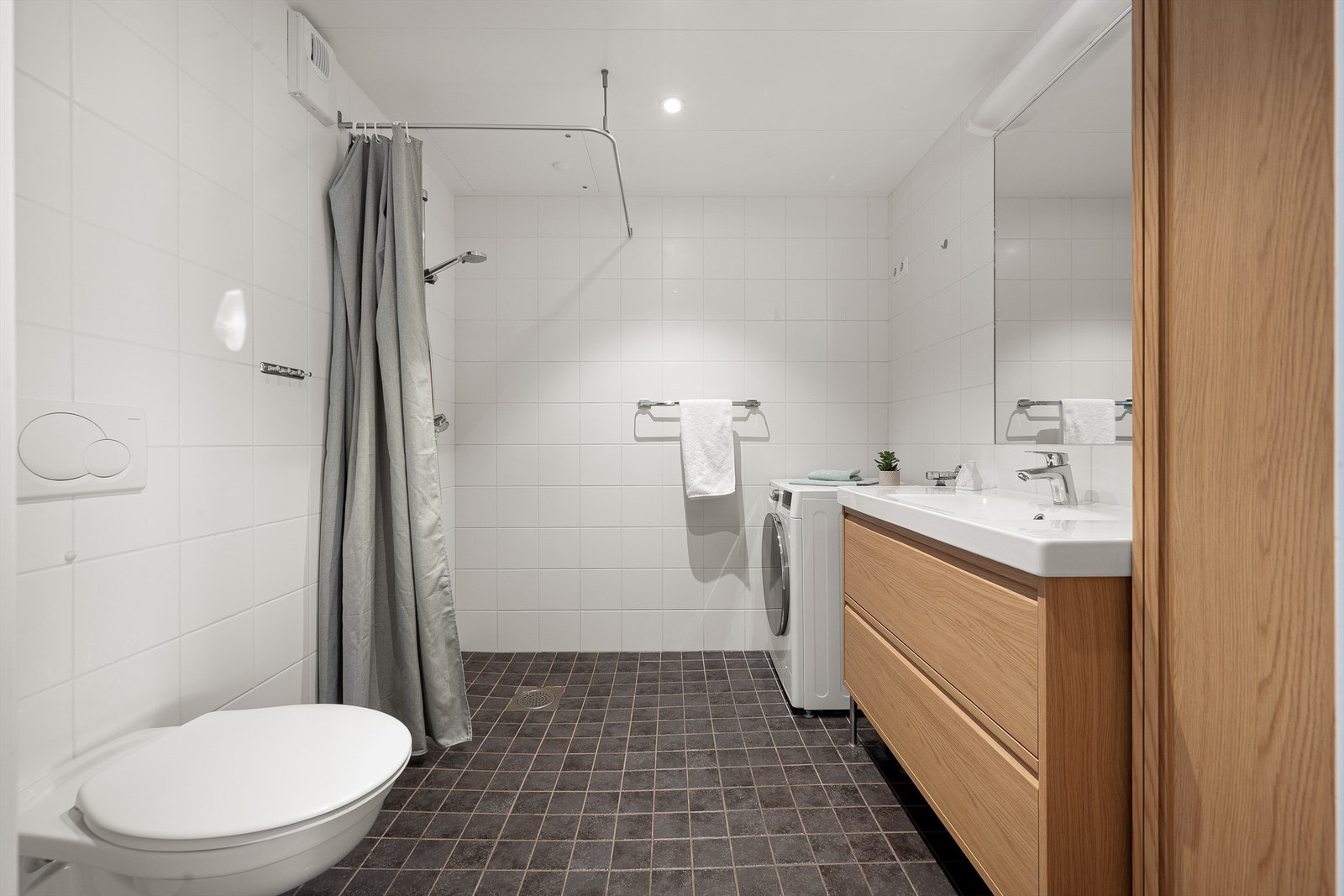 Badet har varmekabler i gulvet og er utstyrt med vegghengt toalett og dusjhjørne. Galleribilde