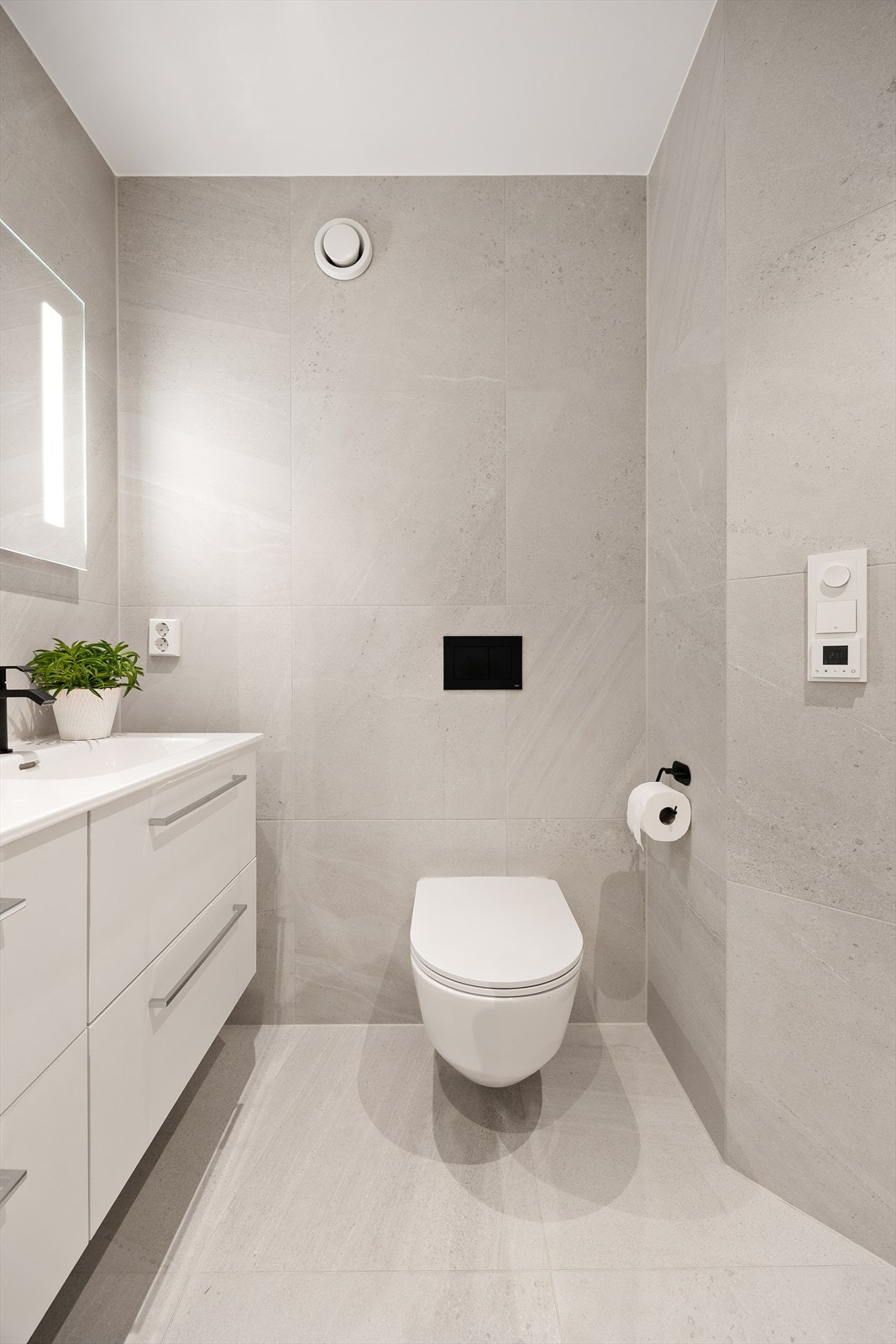 Badet har vegghengt toalett og flislagt gulv med elektriske varmekabler for økt komfort Galleribilde