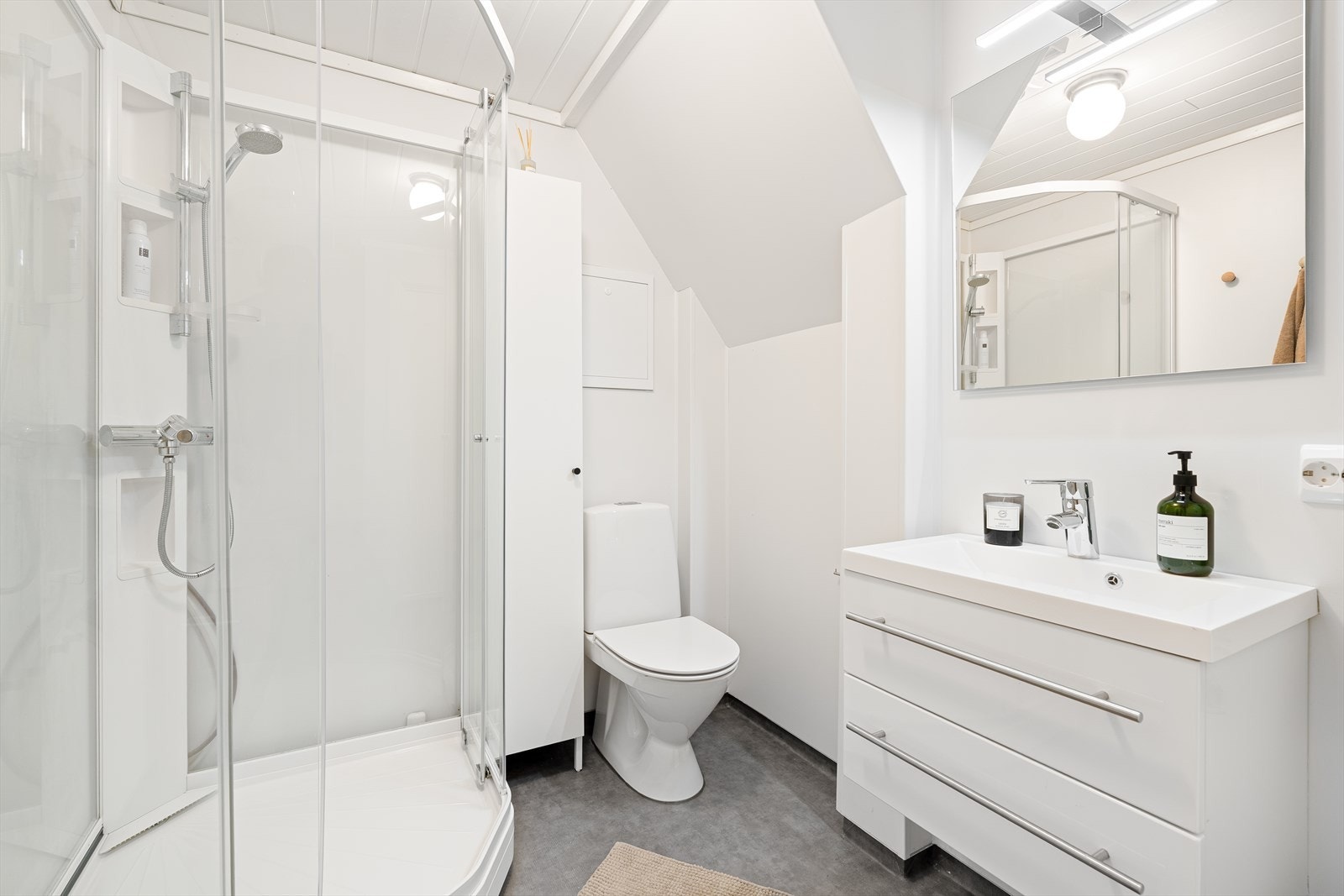 Badet har belegg på gulvet med varmekabler. Det inneholder forøvrig et dusjkabinett, toalett og baderomsinnredning med speil over. Det er opplegg og plass til vaskemaskin på dette badet om ønskelig. Galleribilde