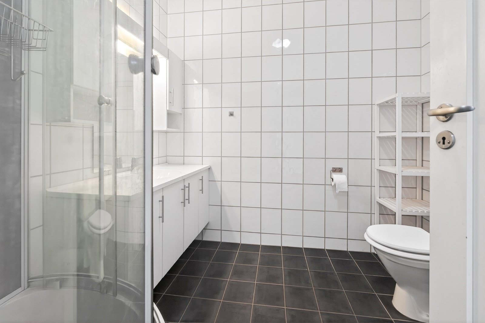 Flislagt bad med heldekkende servant med innredning, wc, dusjkabinett og opplegg til vaskemaskin Galleribilde
