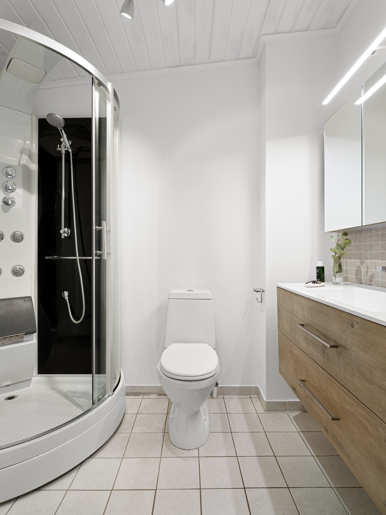 Badet er innredet med servant med baderomsinnredning og speil. Videre er badet utstyrt med dusjkabinett og toalett. Galleribilde