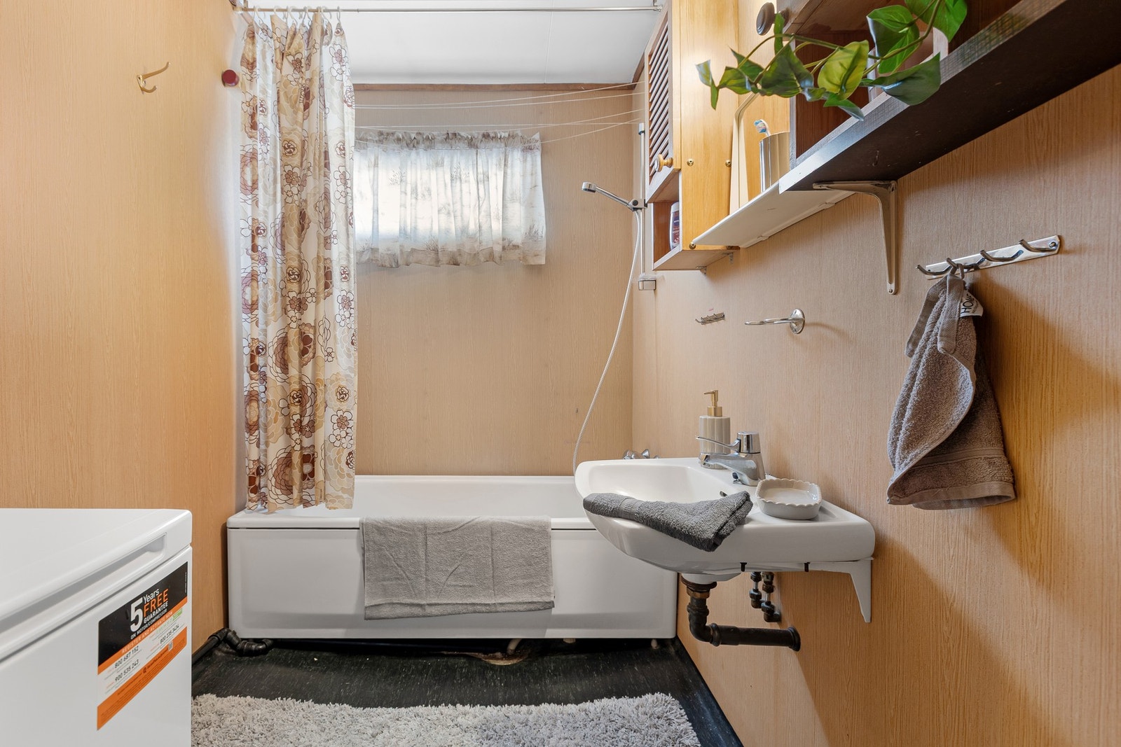 Bad med enkel standard bestående av badekar, servant og opplegg for vaskemaskin. Galleribilde
