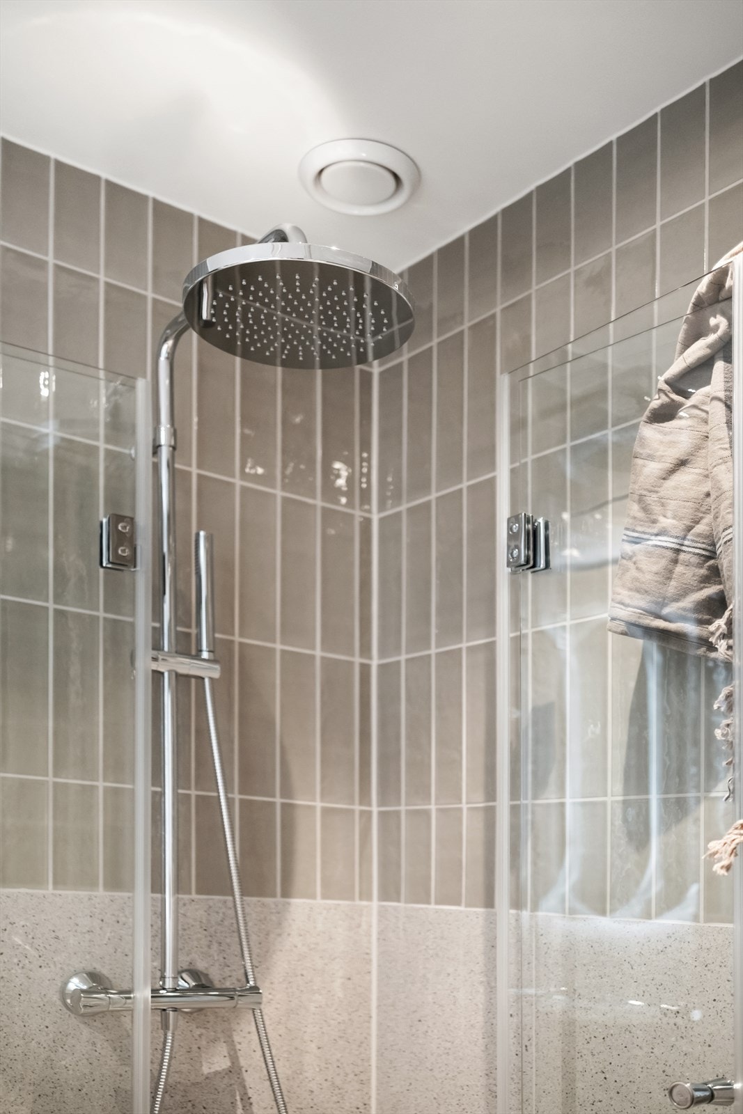 Badet er innredet med dusjhjørne med innfellbare glassdører og armatur med regn- og hånddusj. Galleribilde