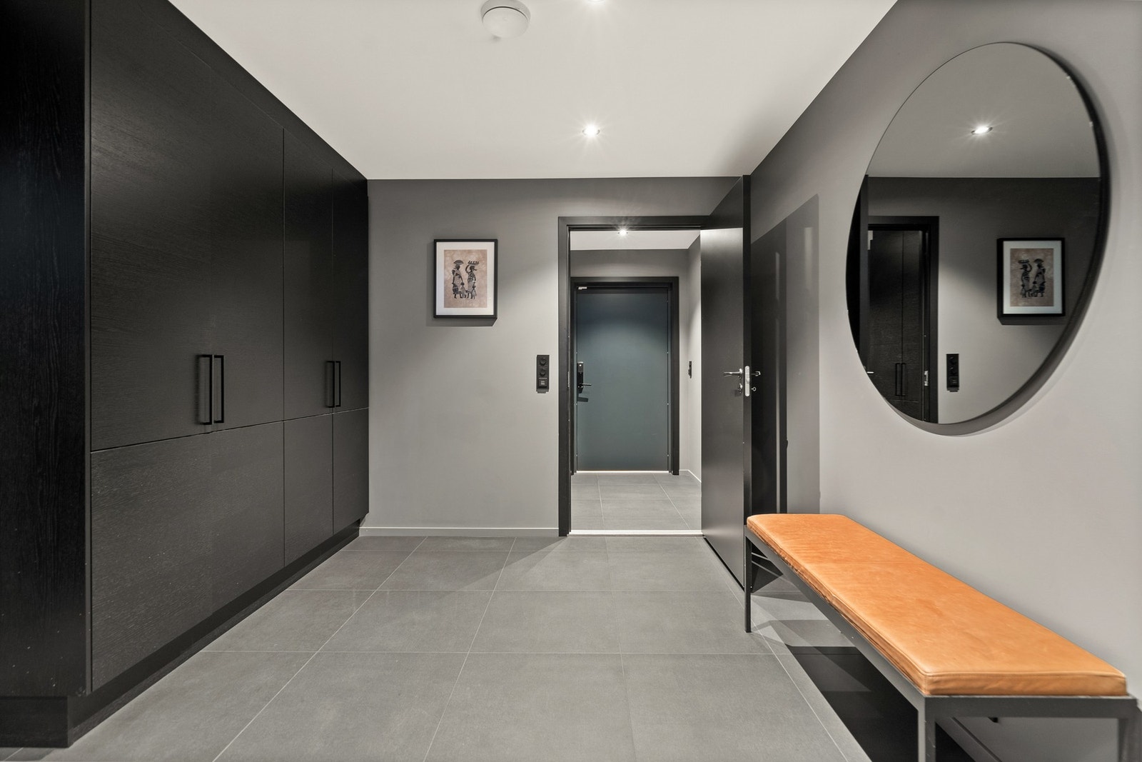 I både entré og hall er det grå gulvfliser. Det er gulvvarme og downlights i himlingen, og både tak- og veggflater er malt i en mørk gråtone. Galleribilde