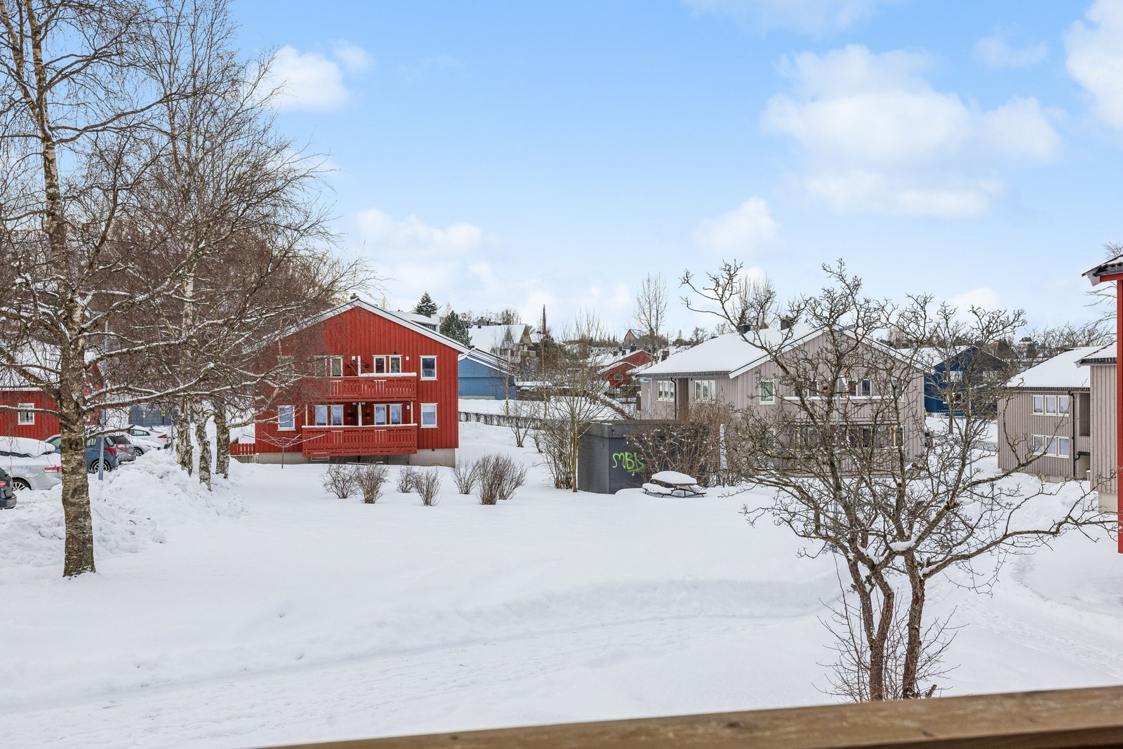 Utsikt fra verandaen mot borettslagets fellesområder, med benker som kan benyttes sommerstid. Borettslaget har fast ansatt vaktmester som ivaretar fellesområdene. Galleribilde