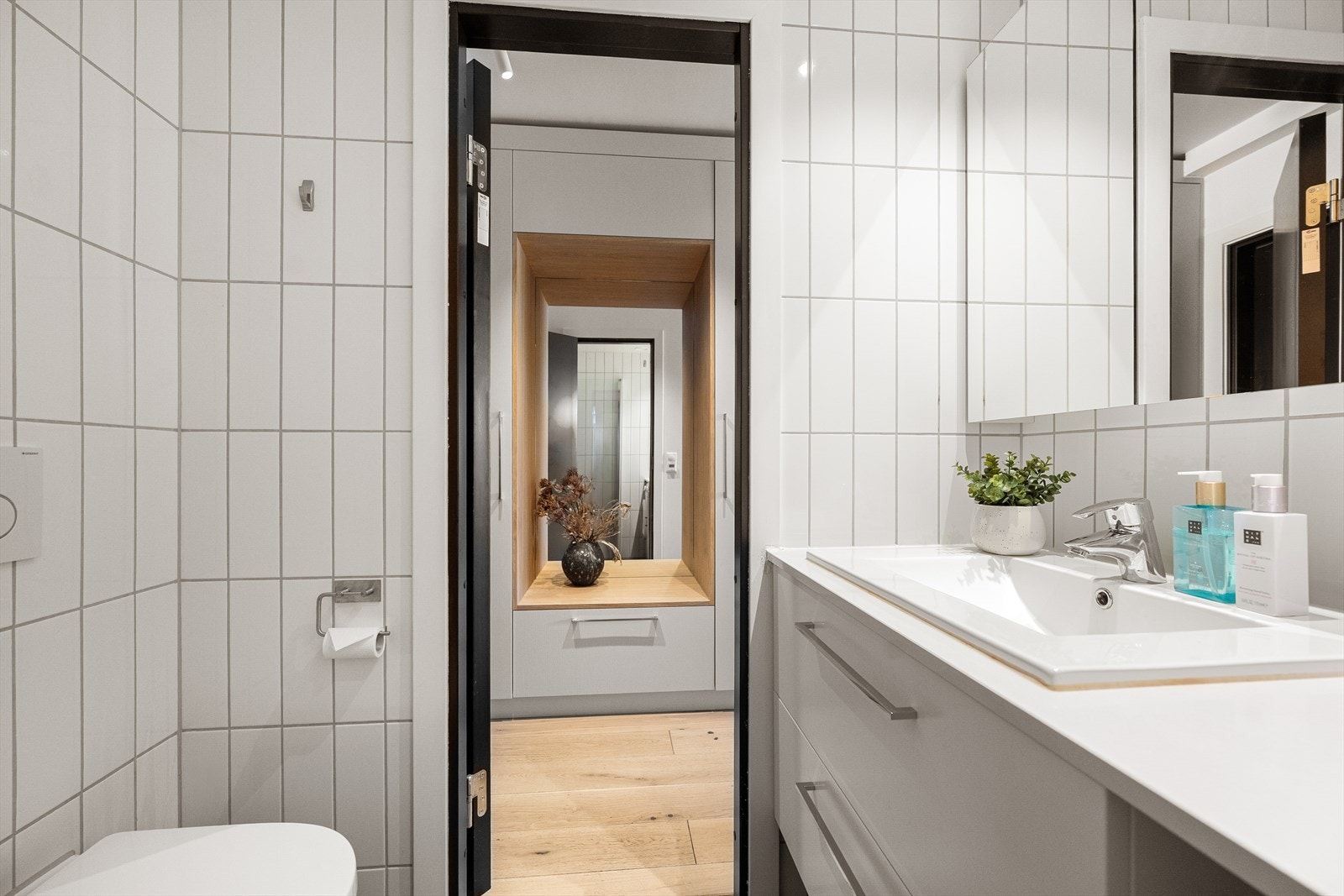 Badet er utstyrt med vegghengt toalett, dusjhjørne og en servantinnredning med skuffer. Galleribilde