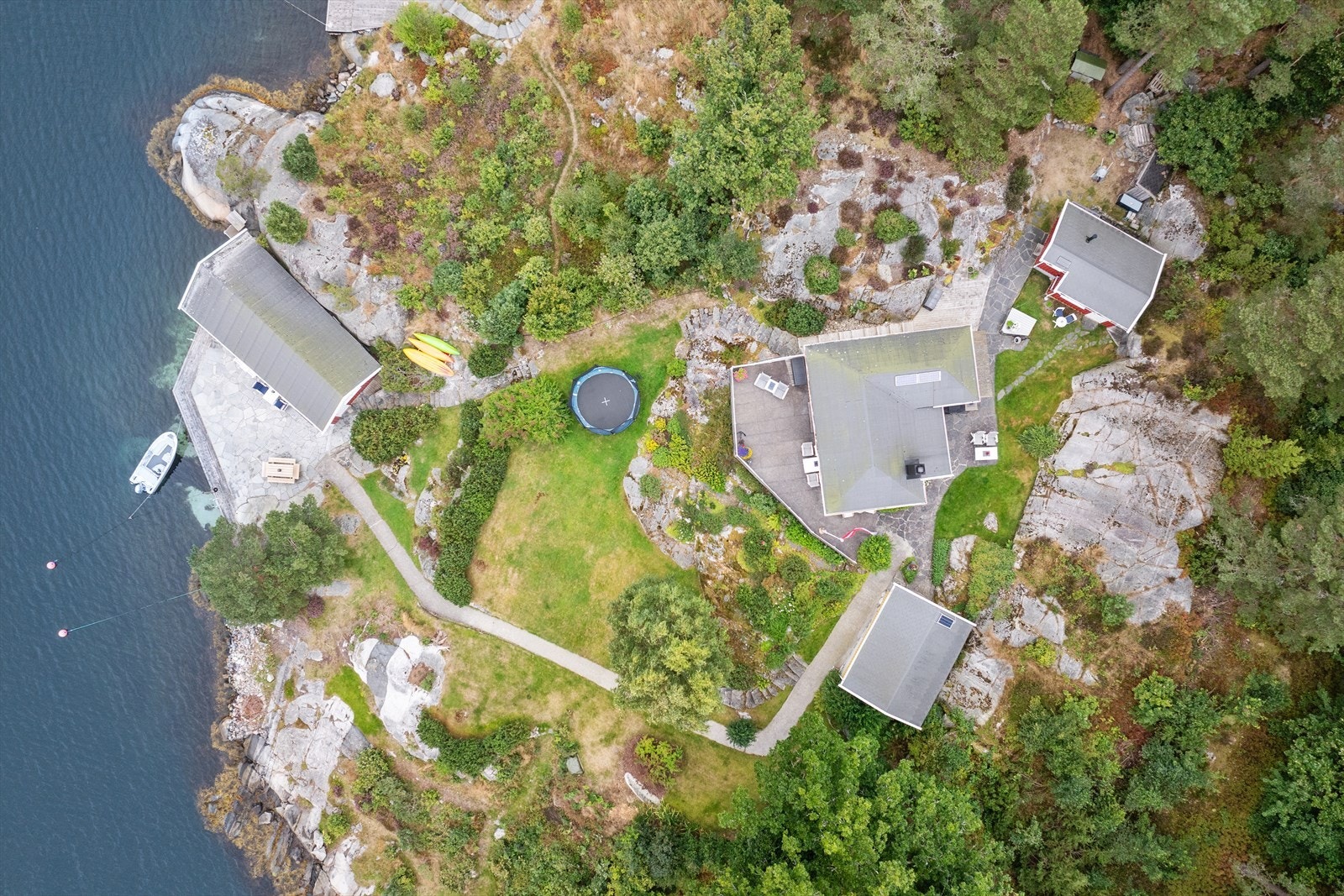 Eiendommen strekker seg langs vannkanten og omfatter flere bygninger på en stor, frodig tomt. Galleribilde