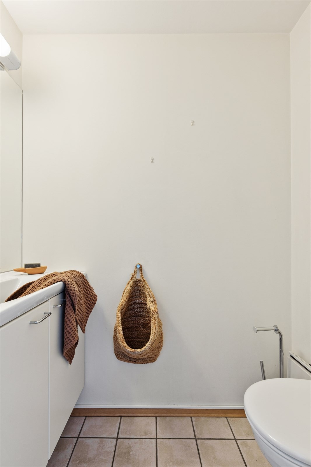 Toalettrom med gulvflate belagt med fliser. Malte veggflater. Malte flater i himling. Vegghengt servantinnredning. Vegghengt toalett. Mekanisk avtrekk med ventil i himling. Galleribilde