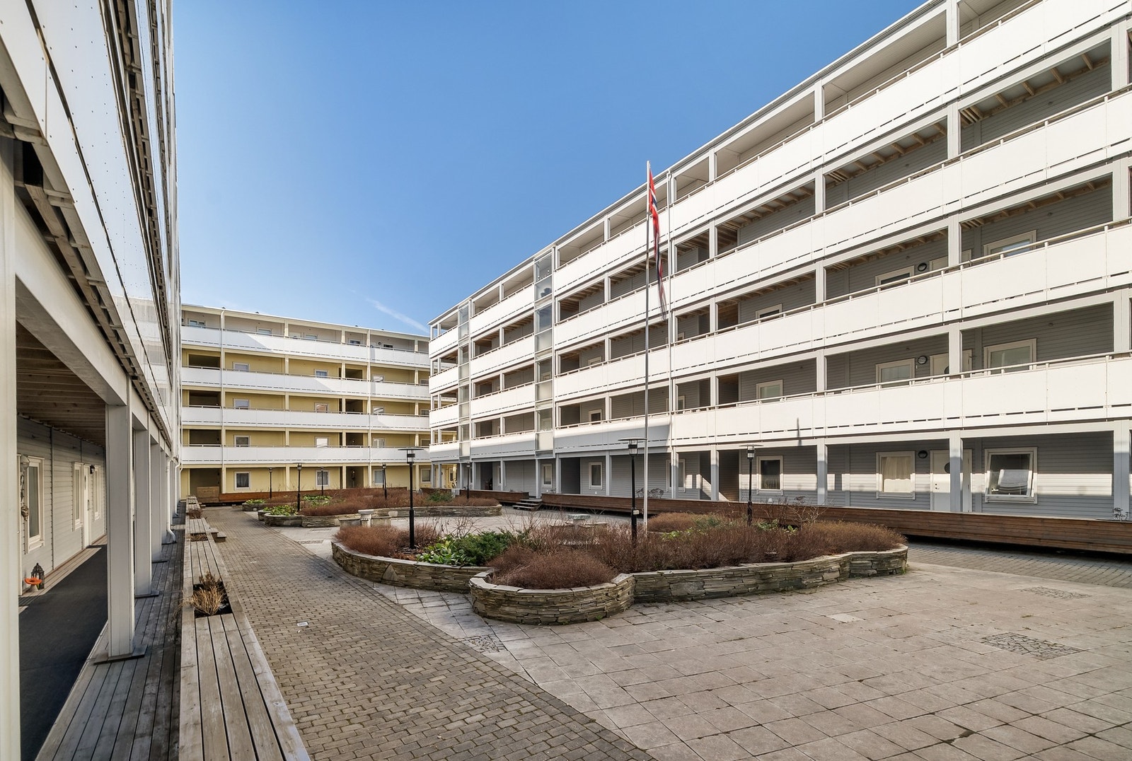 Flott felles uteareal i atrium med beplantning og benker. Galleribilde