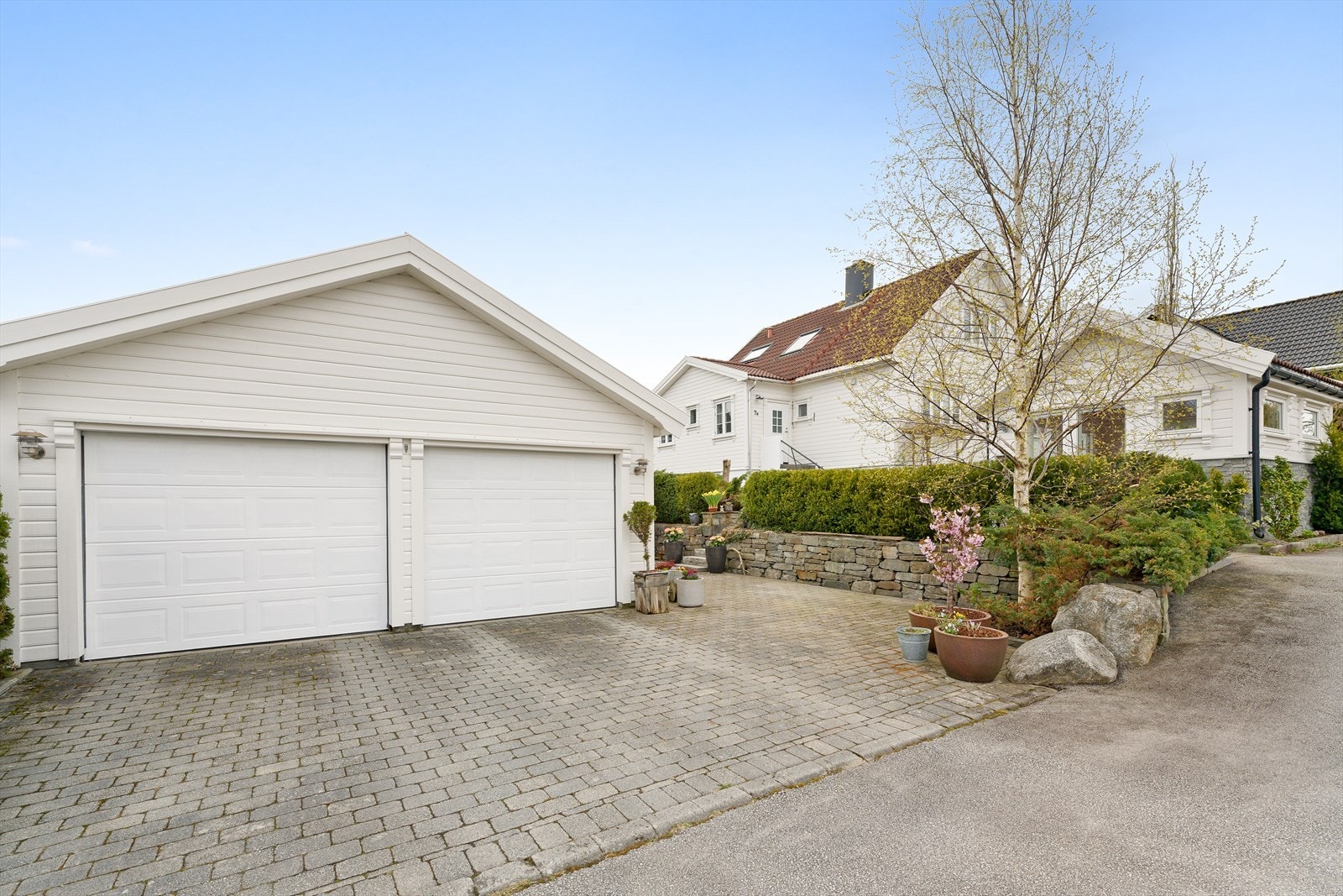 Belegningsstein på gårdsplassen gir et ryddig og solid inntrykk, med enkel adkomst til både bolig og garasje. Galleribilde