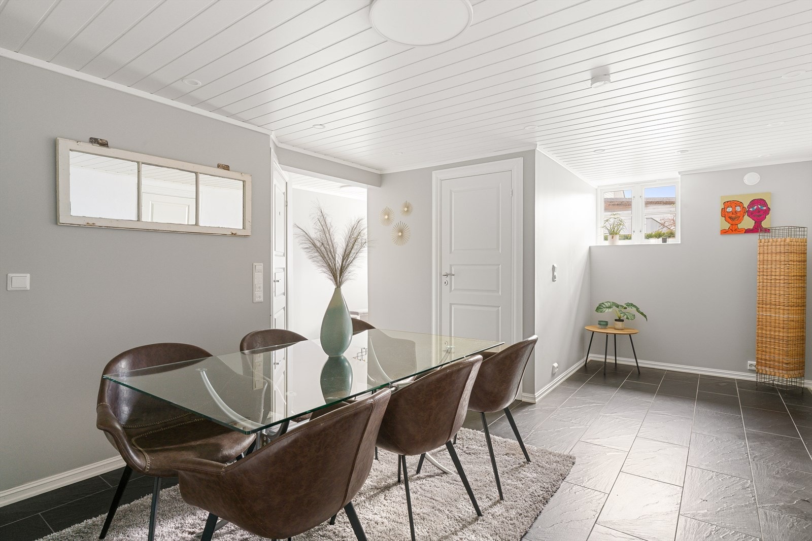 I underetasjen finner vi dette romslige allrommet med flislagt gulv og lysmalte panelplater i taket. Galleribilde