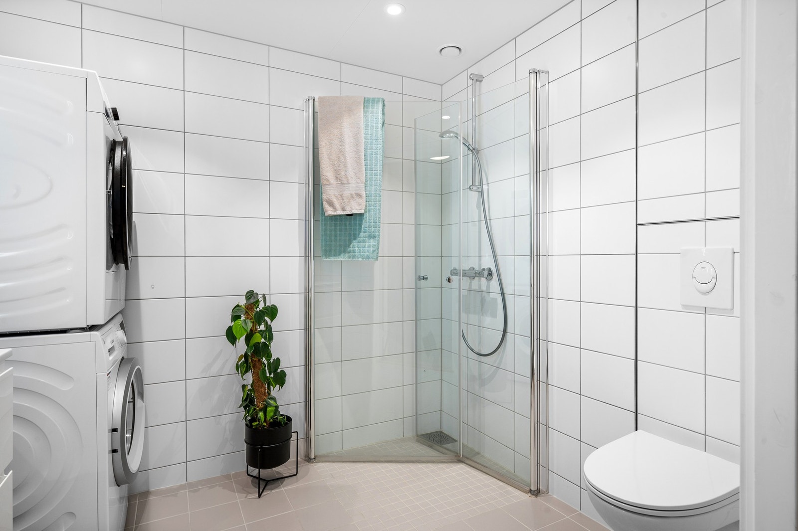 Badet er utstyr med bl.a. 2 stk dusjdører i glass, veggmontert WC, servantplate på underskap og speil samt opplegg for vaskemaskin. Galleribilde