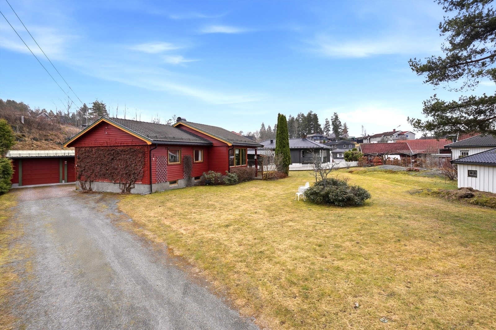 Gruset innkjørsel mot garasjebygning og adkomstparti. Galleribilde