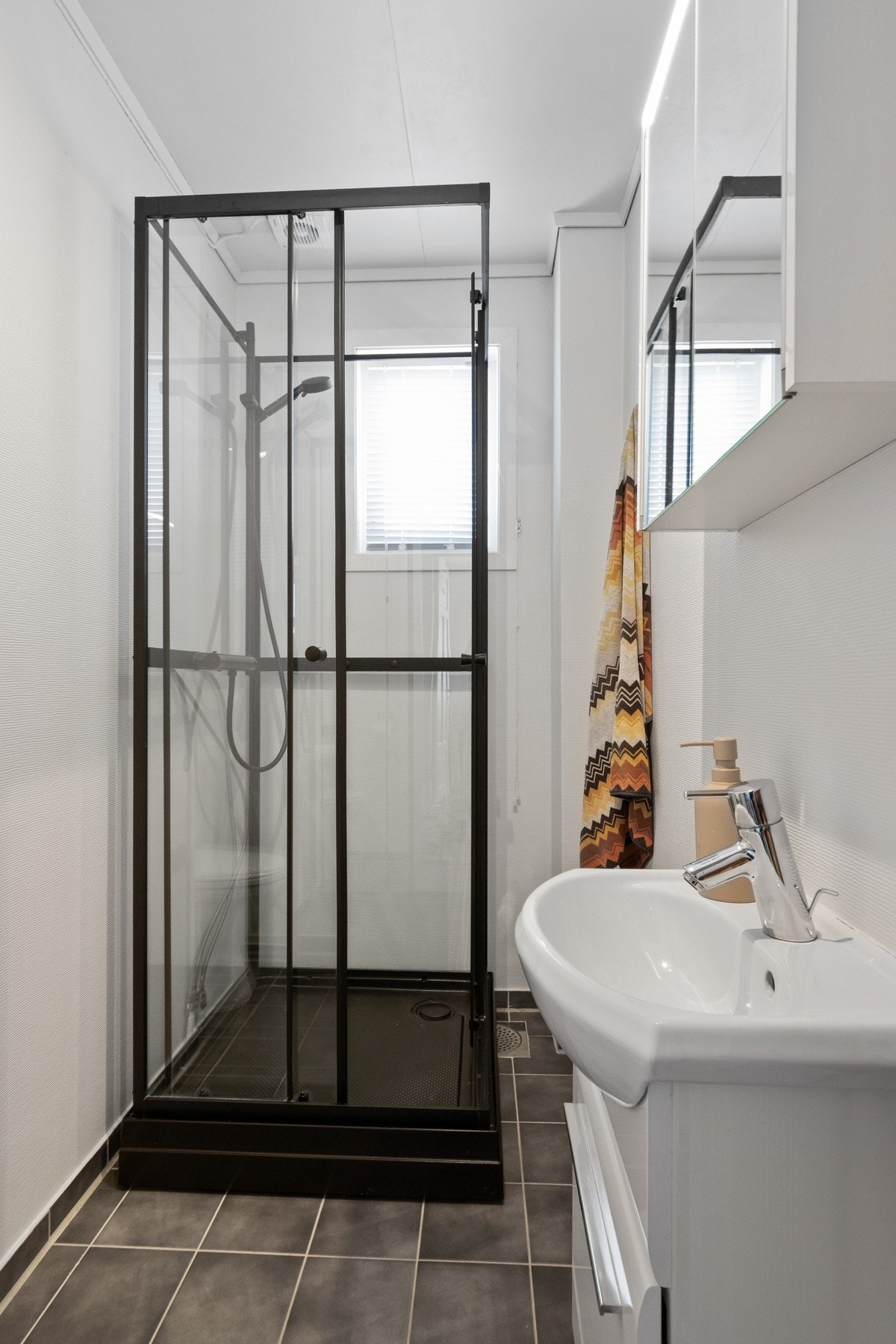 Badet er pusset noe opp i 2012 og har flislagt gulv med varmekabler. Rommet er utstyrt med servant, toalett og dusjkabinett, samt elektrisk fuktstyrt vifte. Galleribilde