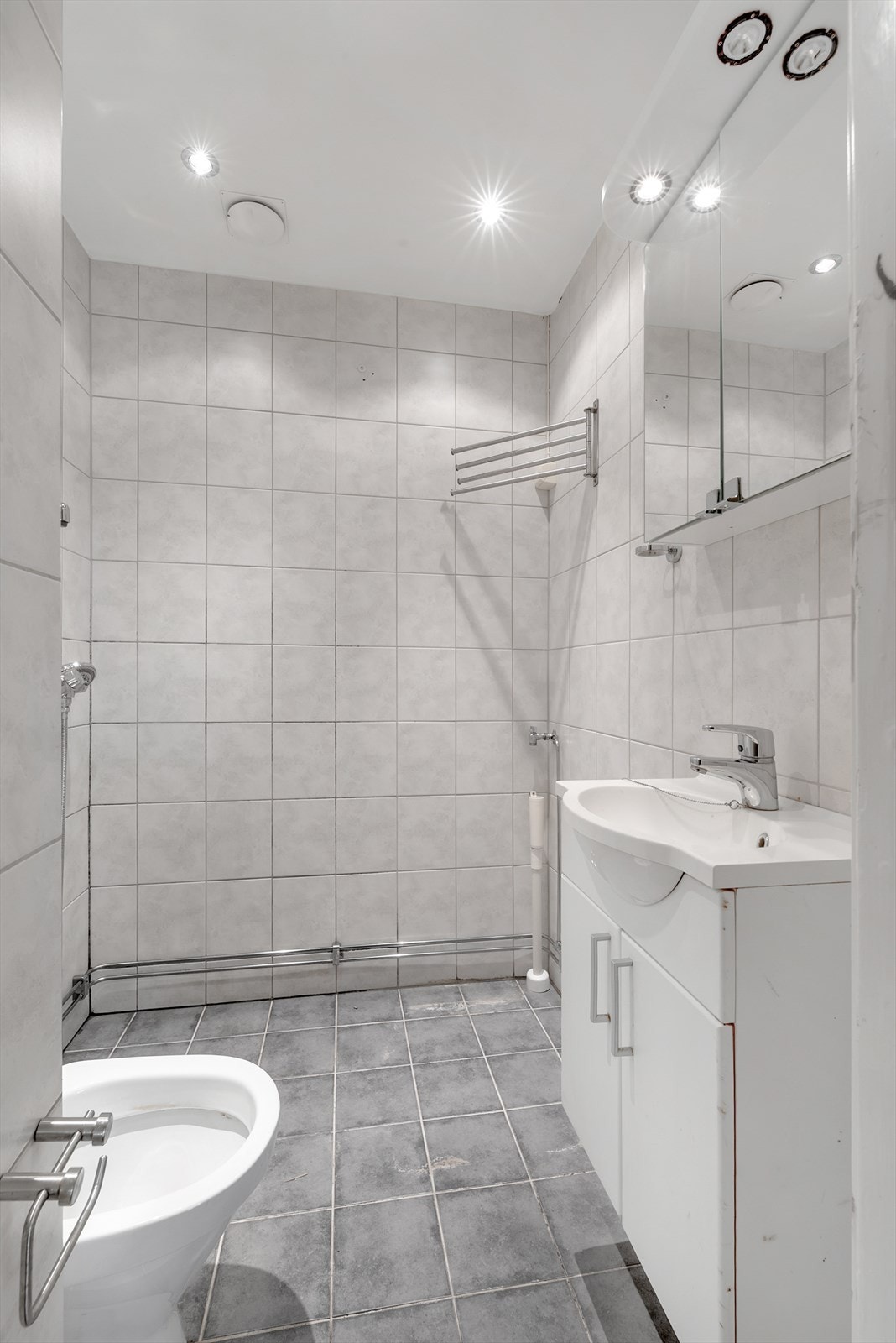 Badet er utstyrt med downlights i himling, opplegg for vaskemaskin og en åpen dusjløsning. Galleribilde