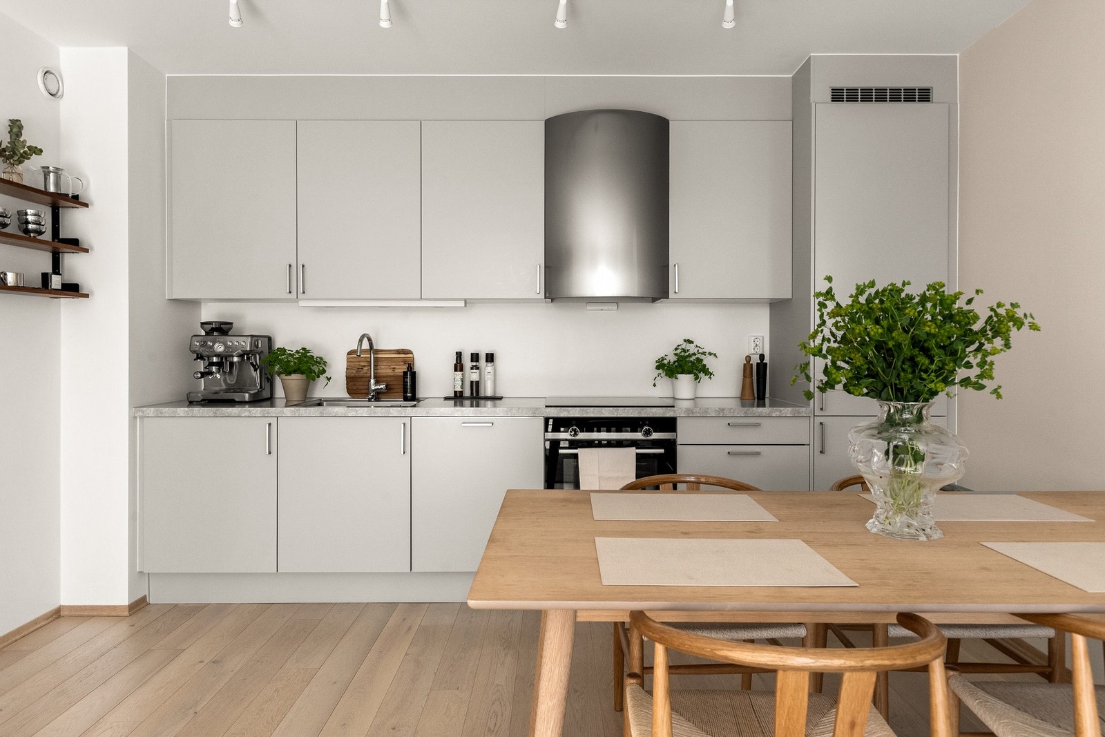 Kjøkkeninnredningen er utstyrt med stilrene grå, glatte fronter og benkeplate i laminat med planlimt kum i rustfritt stål. Galleribilde