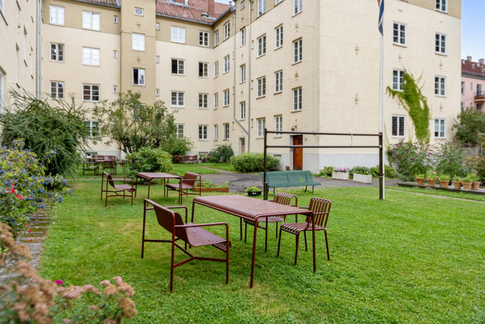Frodig og stor bakgård med mange sittegrupper, moderne sykkelskur og ballbinge. Galleribilde