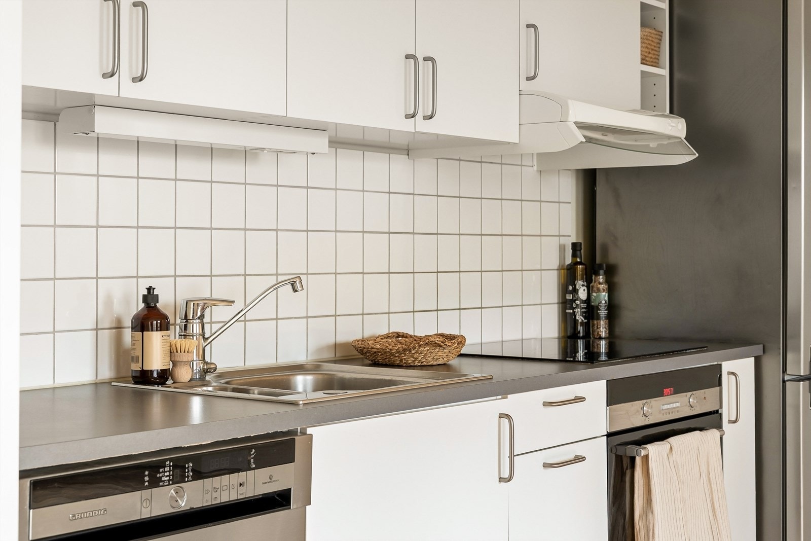 Benkeplaten i laminat gir en slitesterk og praktisk arbeidsflate med god plass til matlaging og forberedelser. Veggflis mellom benkeplate og overskap gir et pent og hygienisk overflatevalg som samtidig beskytter veggen der det trengs mest. Galleribilde