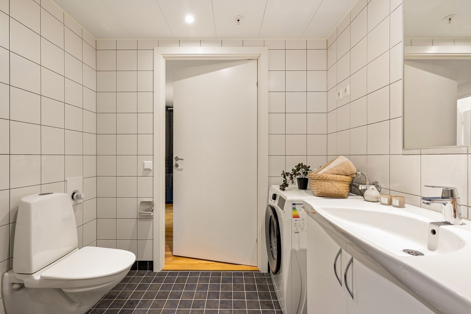 Veggene er kledd med fliser som både er praktiske og estetisk tiltalende, mens himlingen i stål-/aluminiumsplater med integrerte downlights gir rommet et moderne uttrykk og sørger for behagelig, jevn belysning. Galleribilde