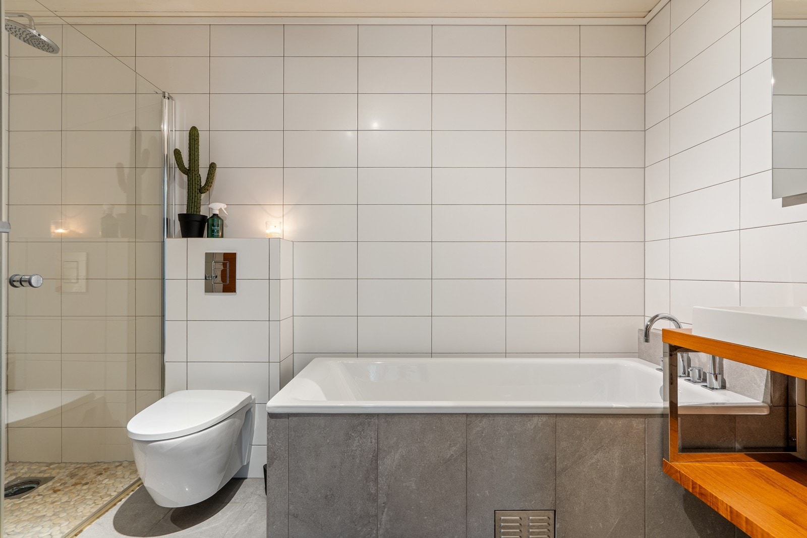 Badet i underetasjen er lekkert og moderne, med fliser på både vegger og gulv, vegghengt wc, dusj med glassdører og badekar Galleribilde