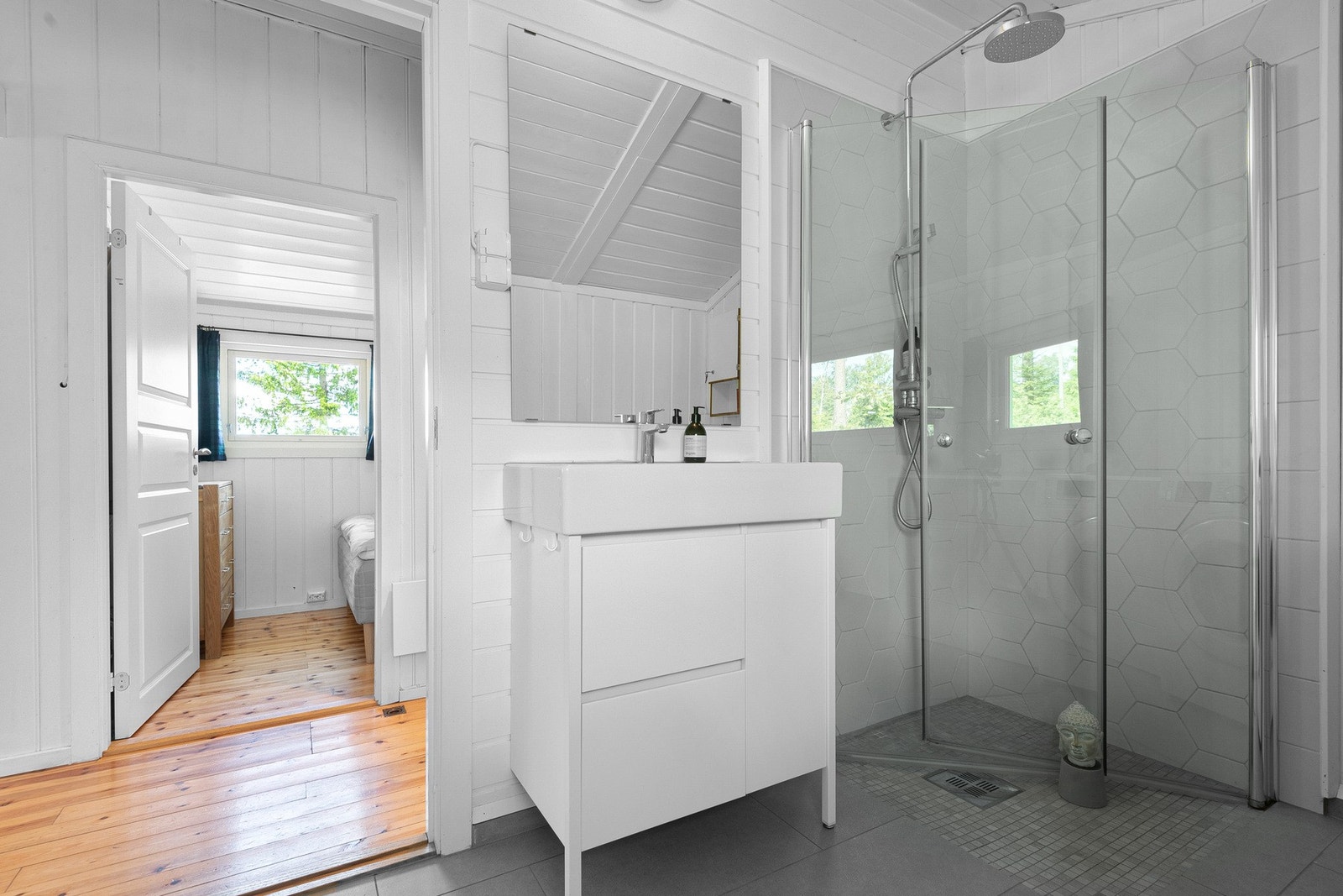 Videre inneholder badet vegghengt toalett og et dusjhjørne med innfellbare dører, utstyrt med både hånddusj og regndusj. Galleribilde