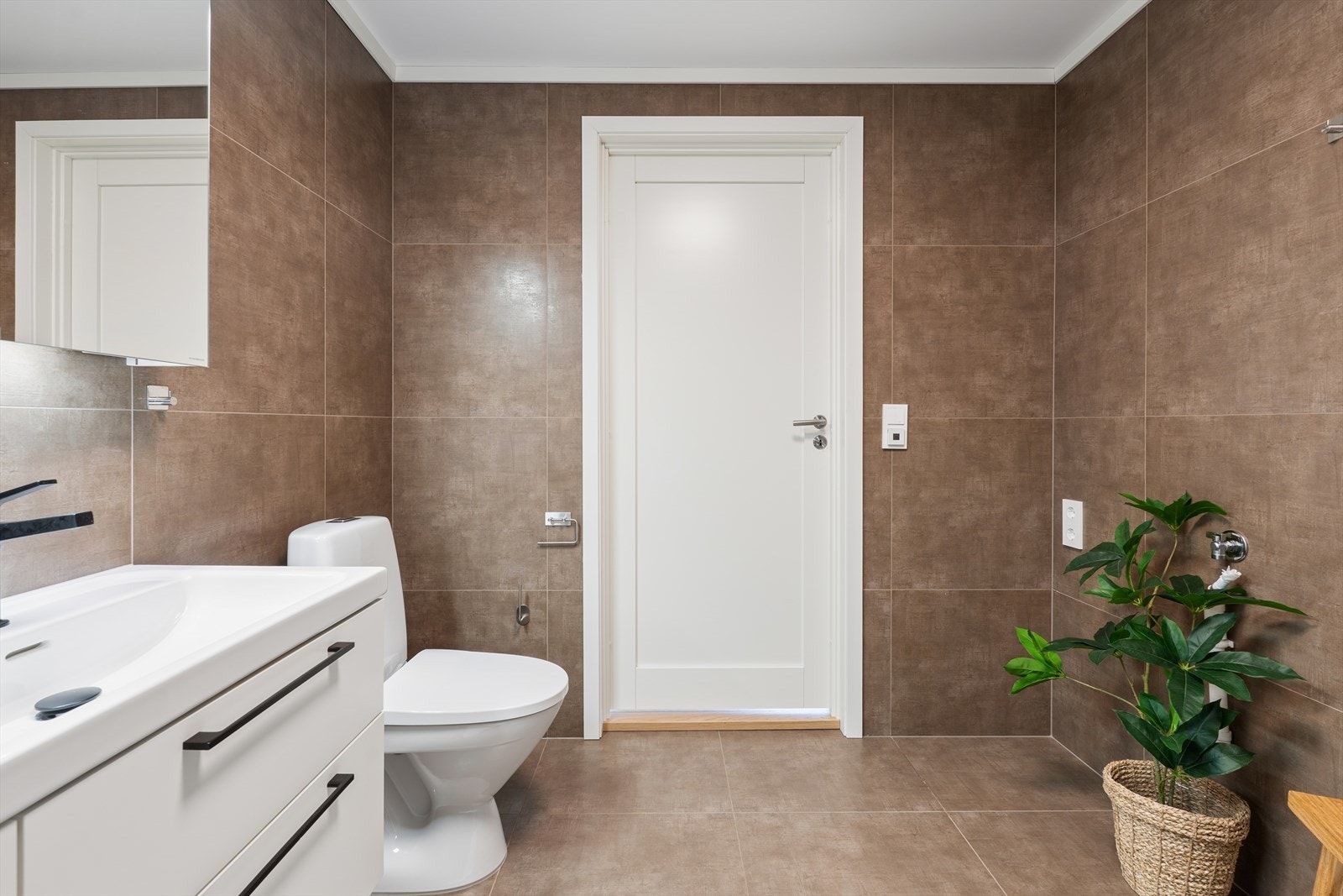 Badet er kombinert vaskerom med opplegg for vaskemaskin. Rommet har mekanisk avtrekk som del av boligens balanserte ventilasjonsanlegg fra 2024. Galleribilde